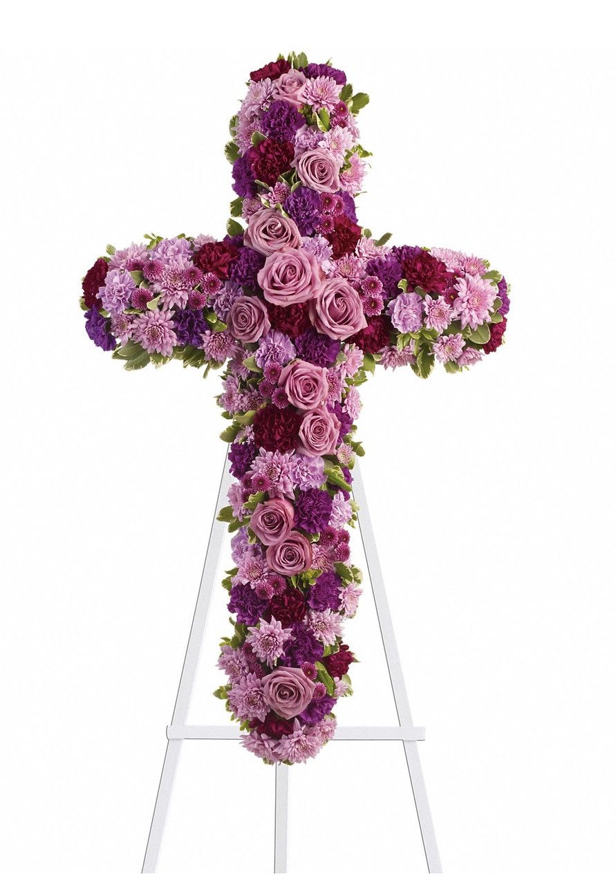 Cross-shaped floral tribute in pink, purple, and burgundy flowers on an easel