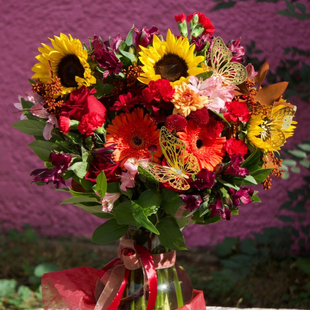 Bright mixed bouquet with sunflowers, gerbera daisies, and a glass vase