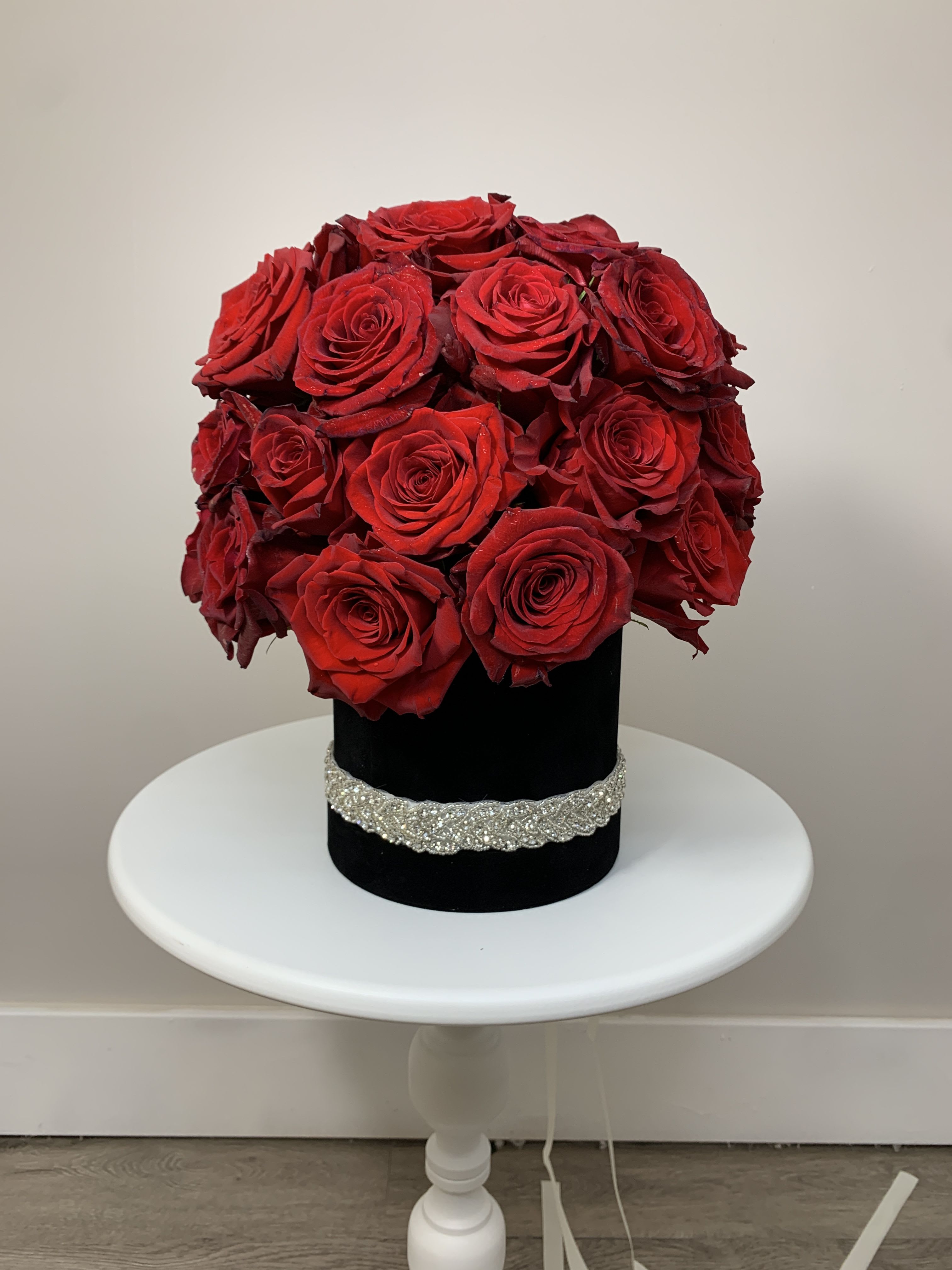 Red rose arrangement in a black hat box with a silver band