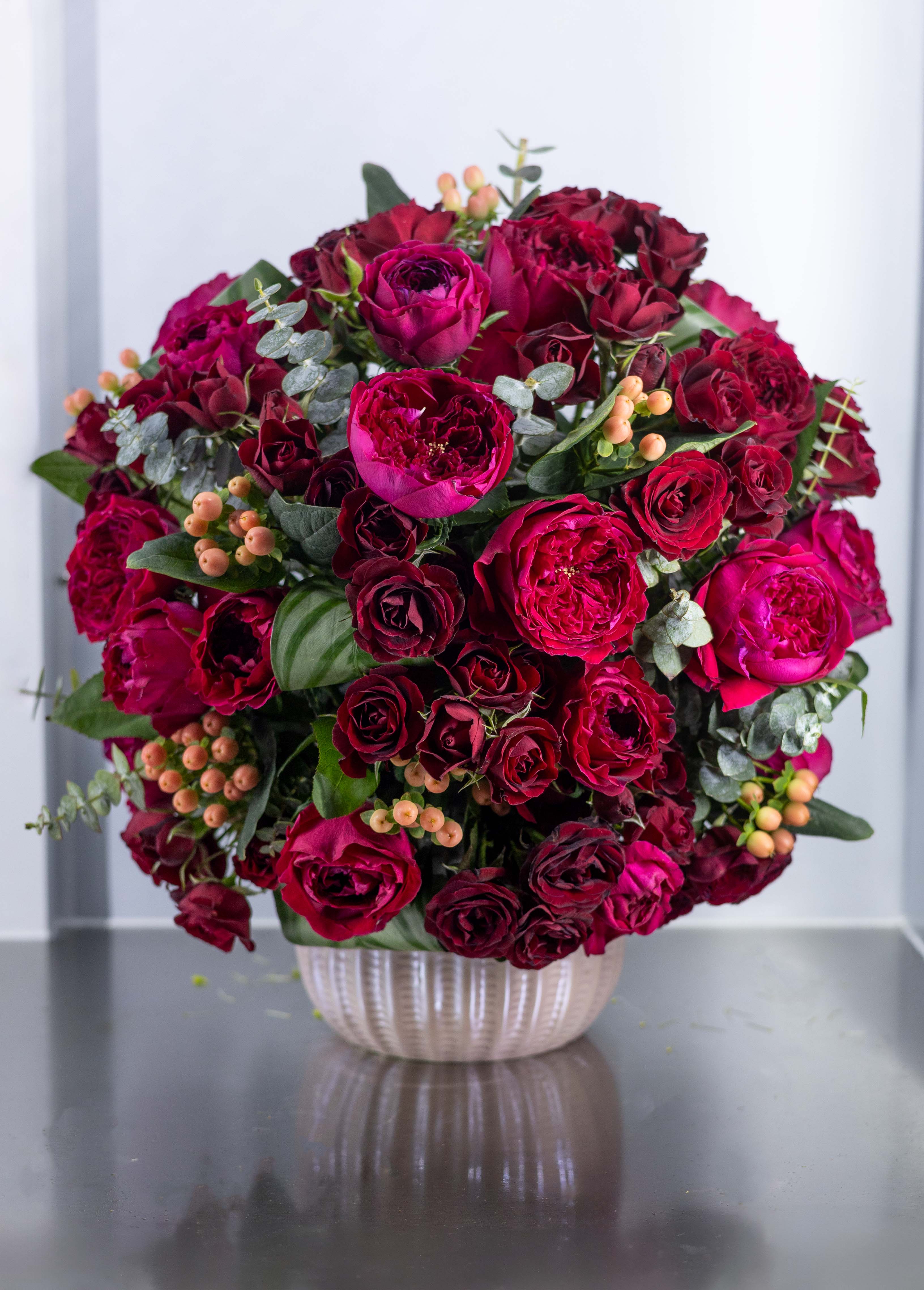 Bouquet of deep pink and burgundy roses in a white vase