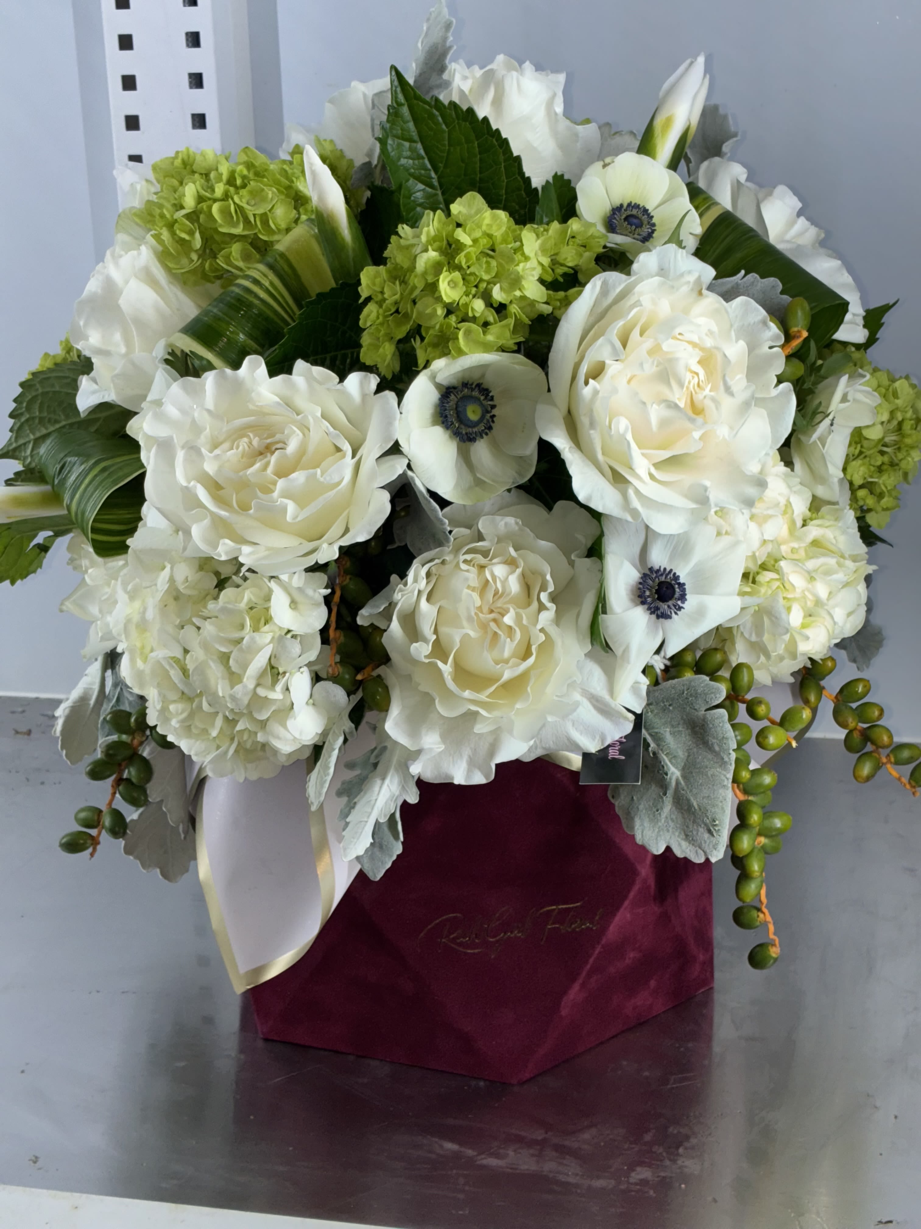 White roses and green hydrangeas in a burgundy box