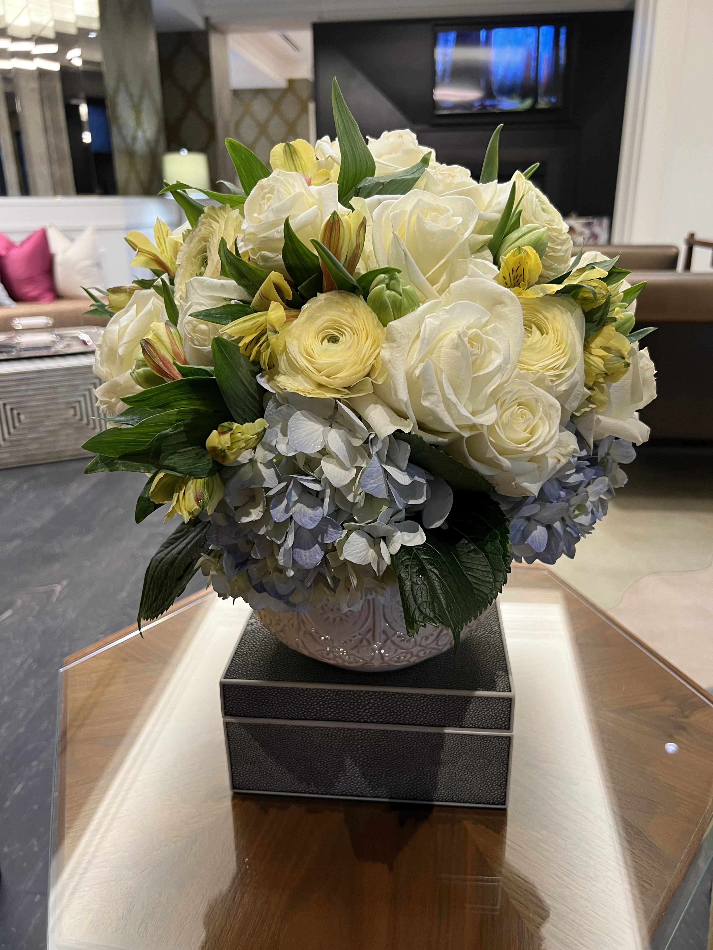 White roses and yellow flowers arranged in a decorative vase