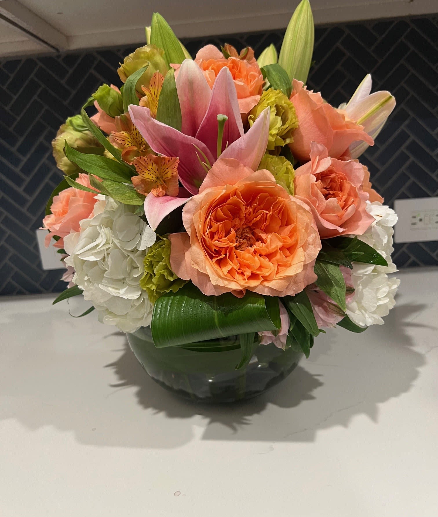 Bouquet of orange and pink flowers in a glass bowl vase