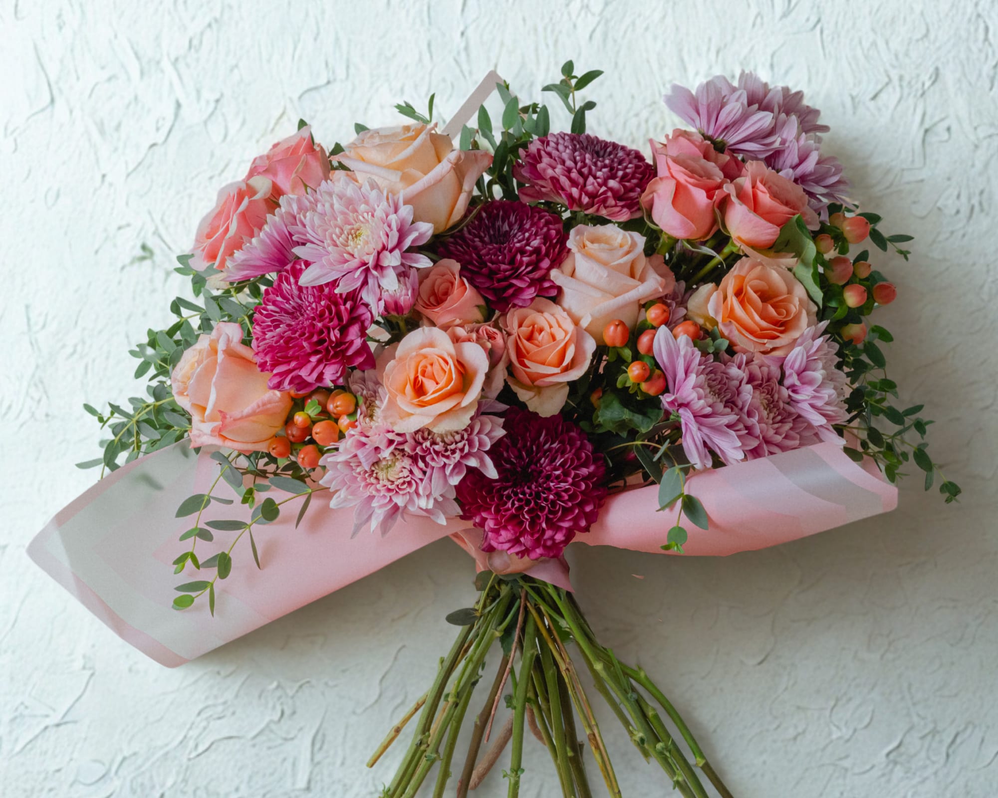 Berry Peach Flower Bouquet - The bouquet is elegantly cradled in premium blush-pink frosted wrapping with subtle architectural folds, giving it a chic, contemporary silhouette. 
