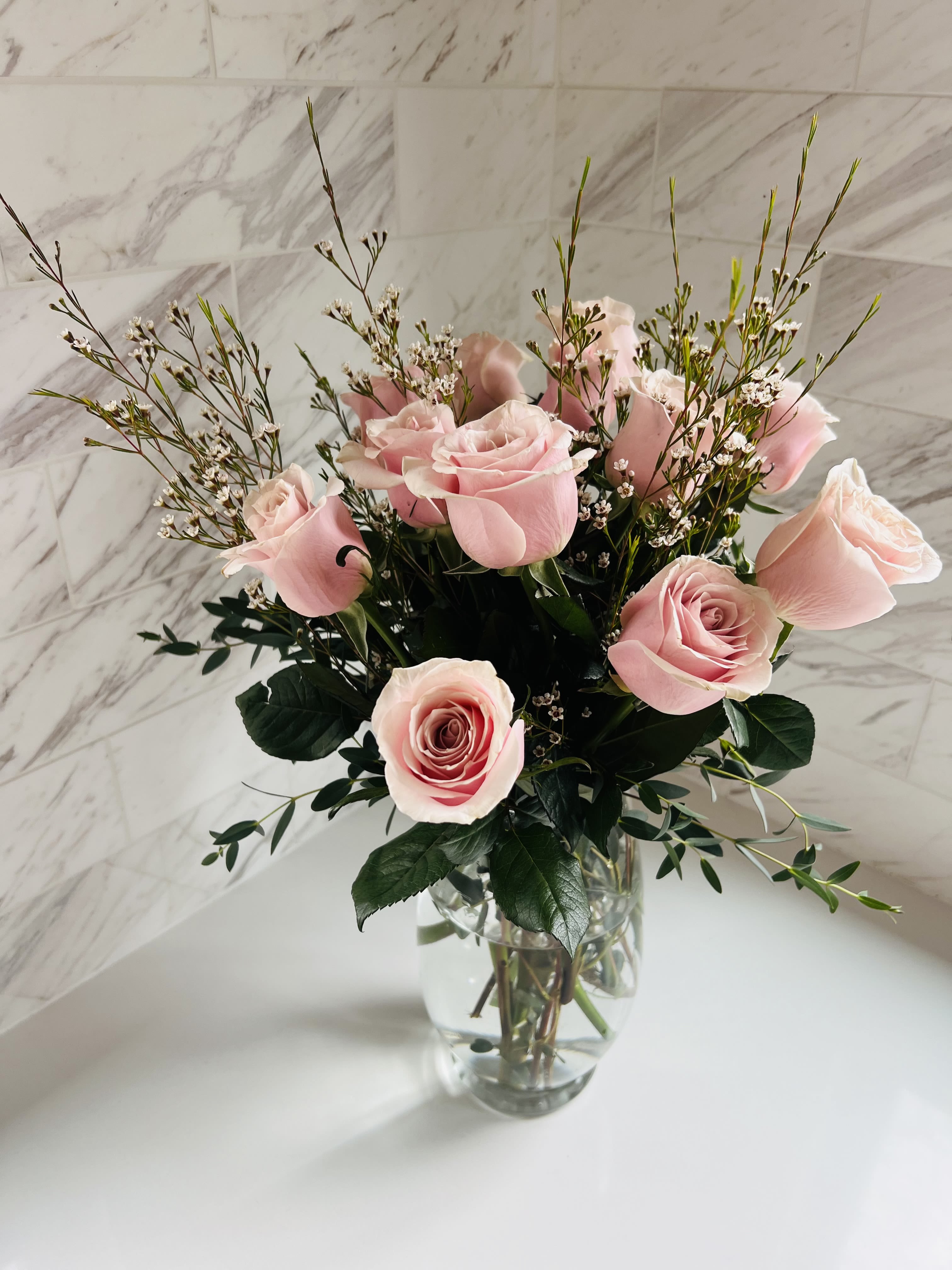 Pink roses arranged in a clear glass vase with airy filler flowers