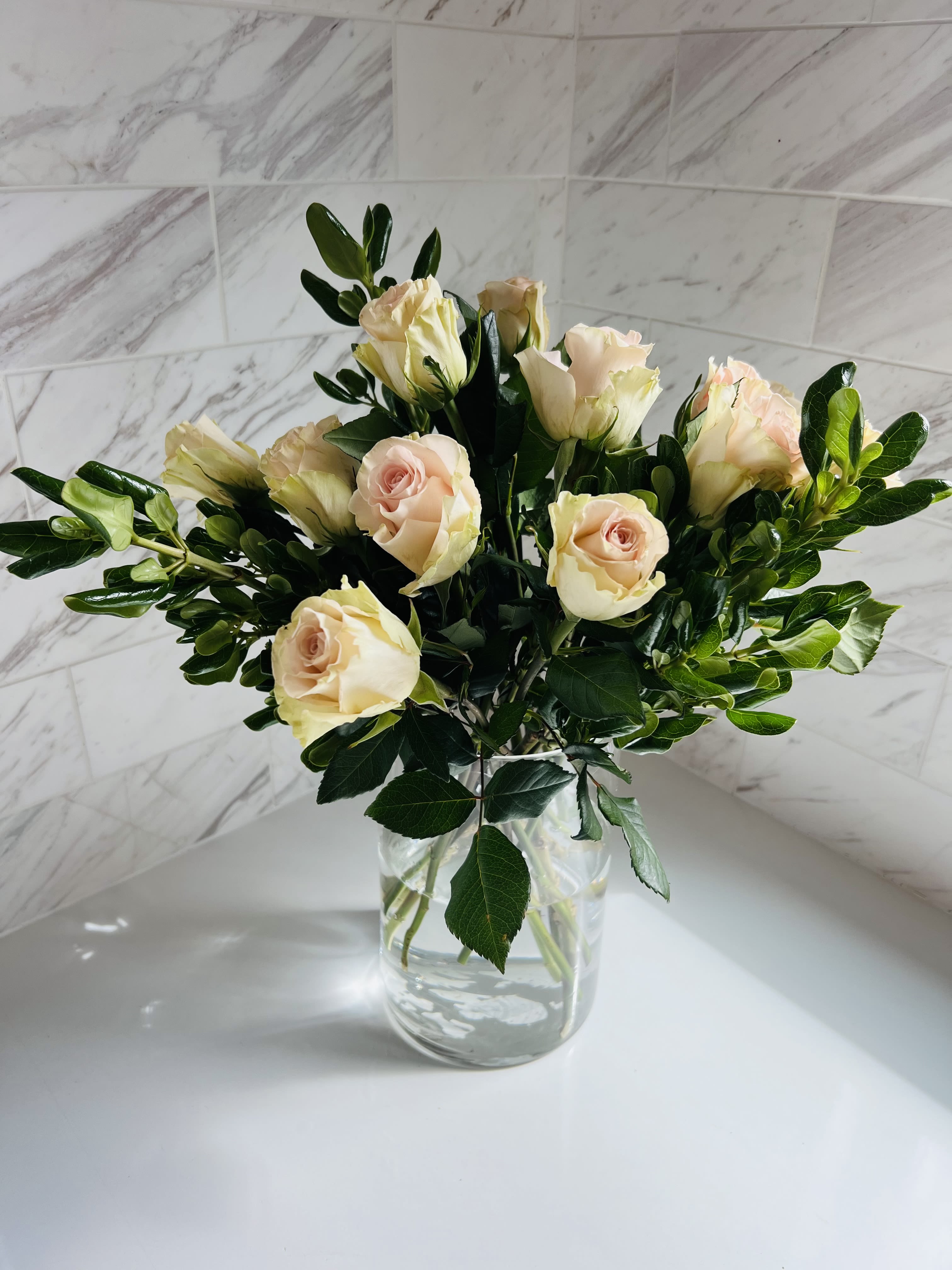 Pale peach roses arranged in a clear glass vase