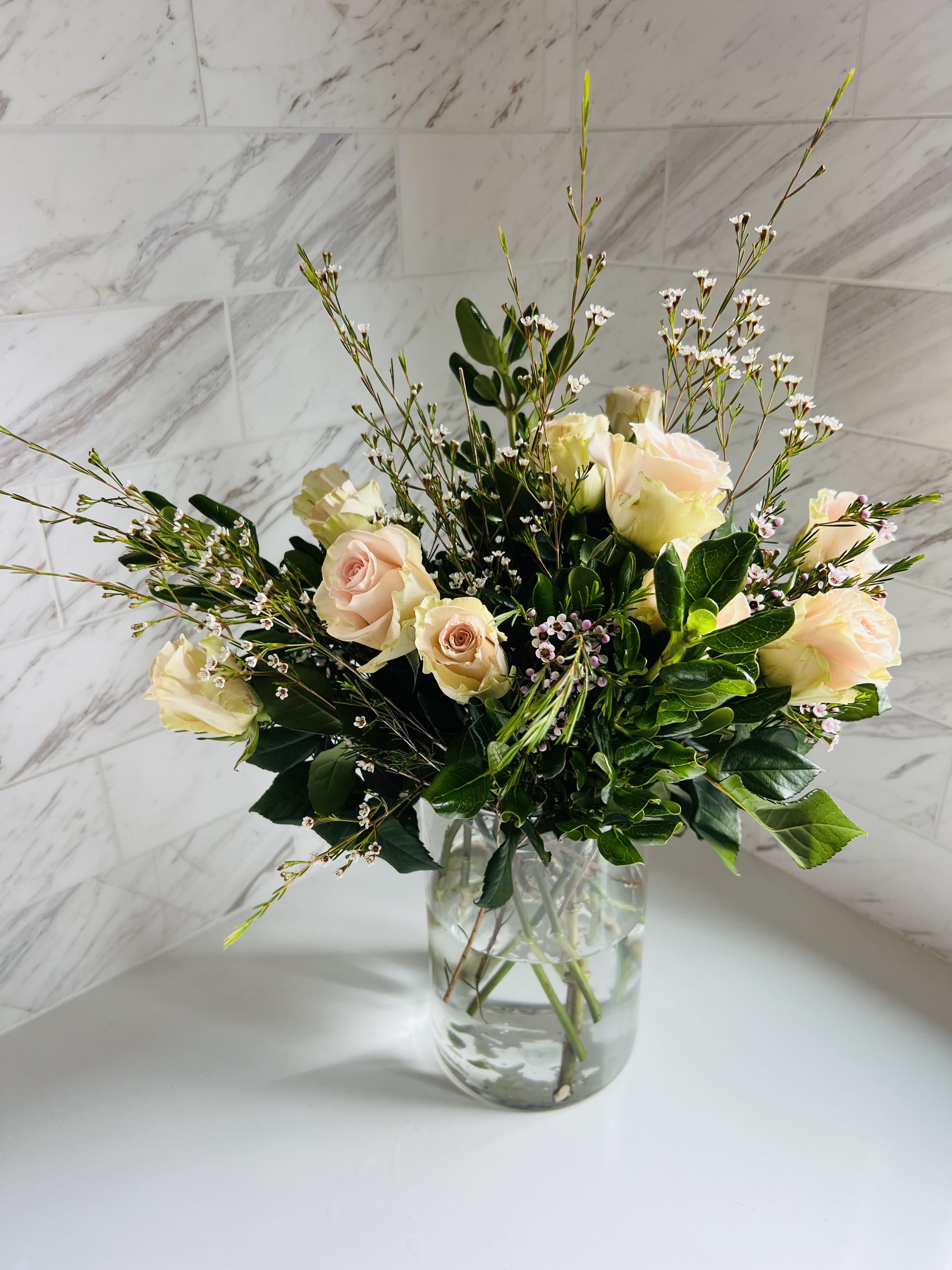 Cream roses arranged in a clear glass vase with airy filler flowers