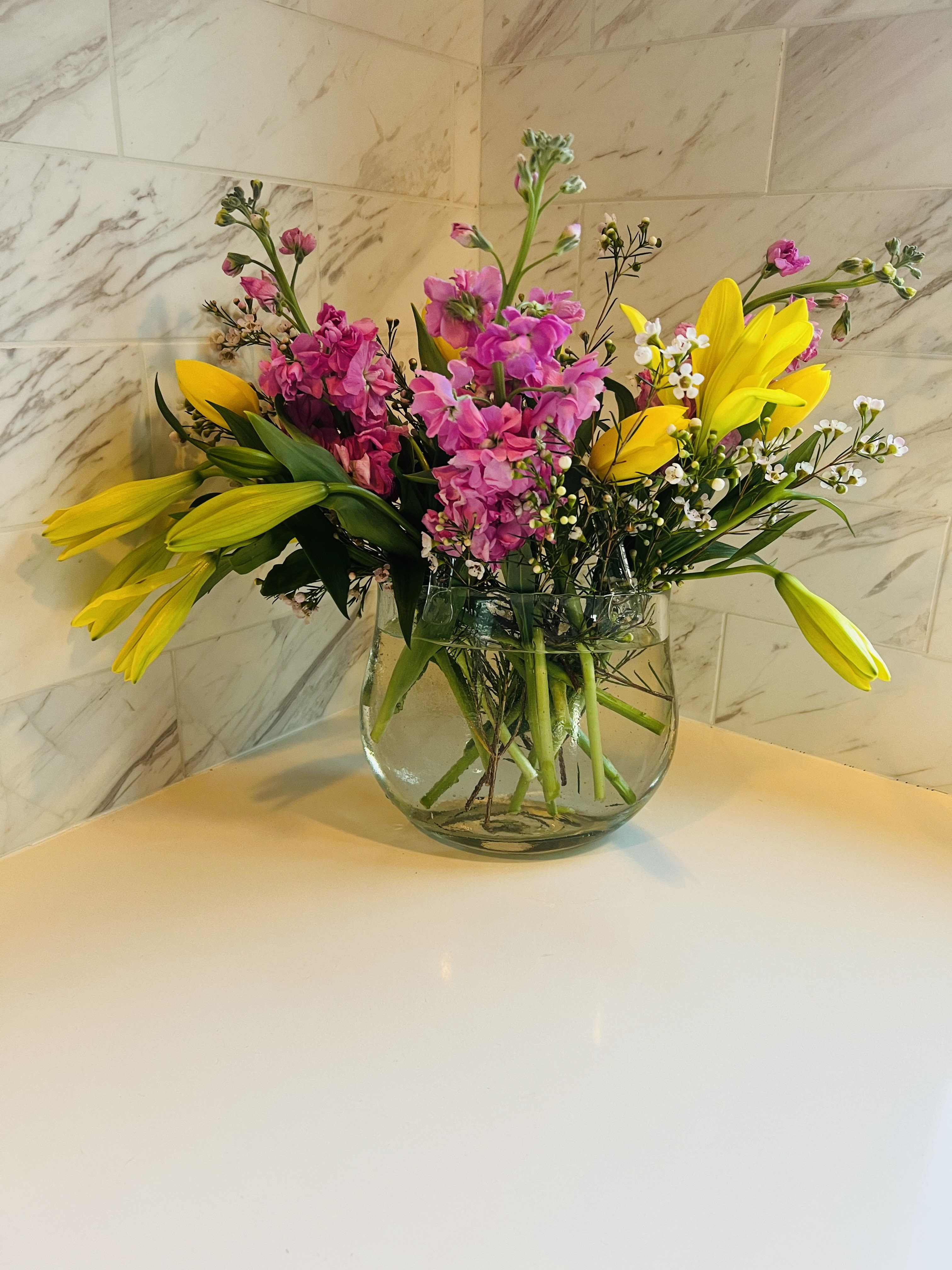 Bouquet of pink and yellow flowers in a clear glass vase
