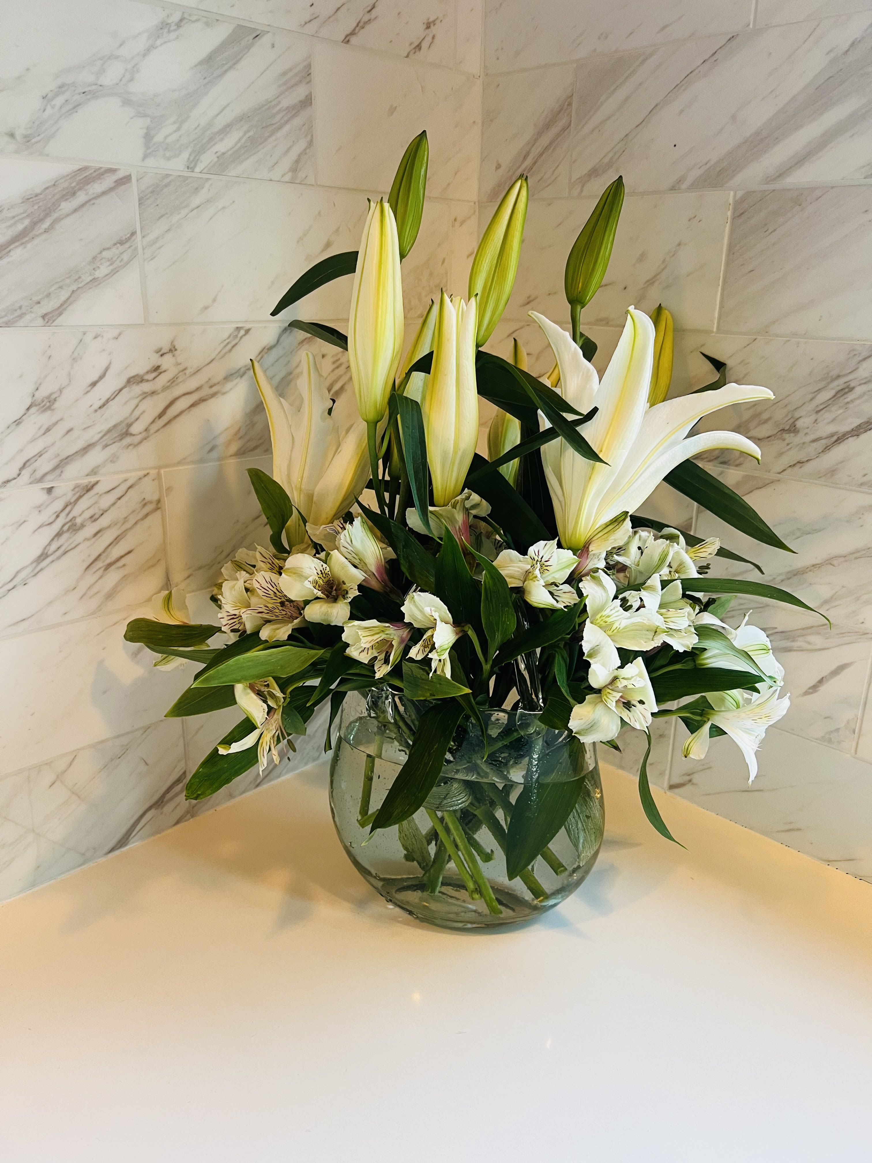 White lilies and alstroemeria arranged in a clear glass vase