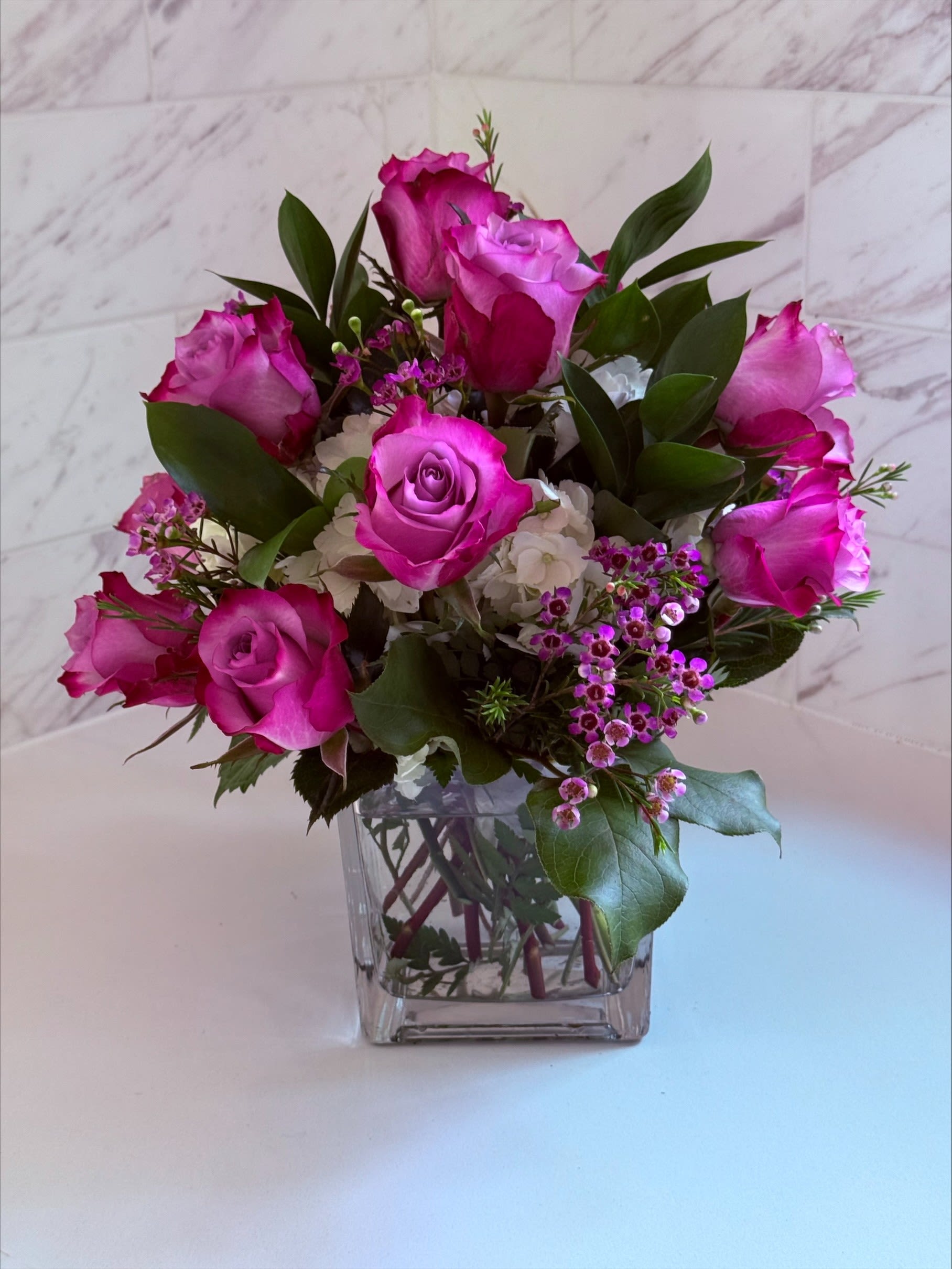 Pink roses arranged in a clear square glass vase