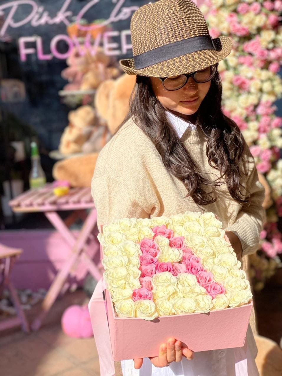 Woman holding a pink box filled with cream and pink roses