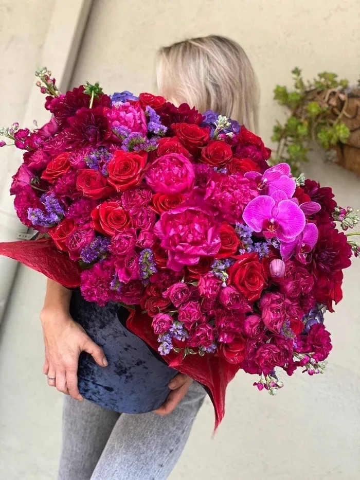 Large bouquet of red, pink, and purple flowers held by a person