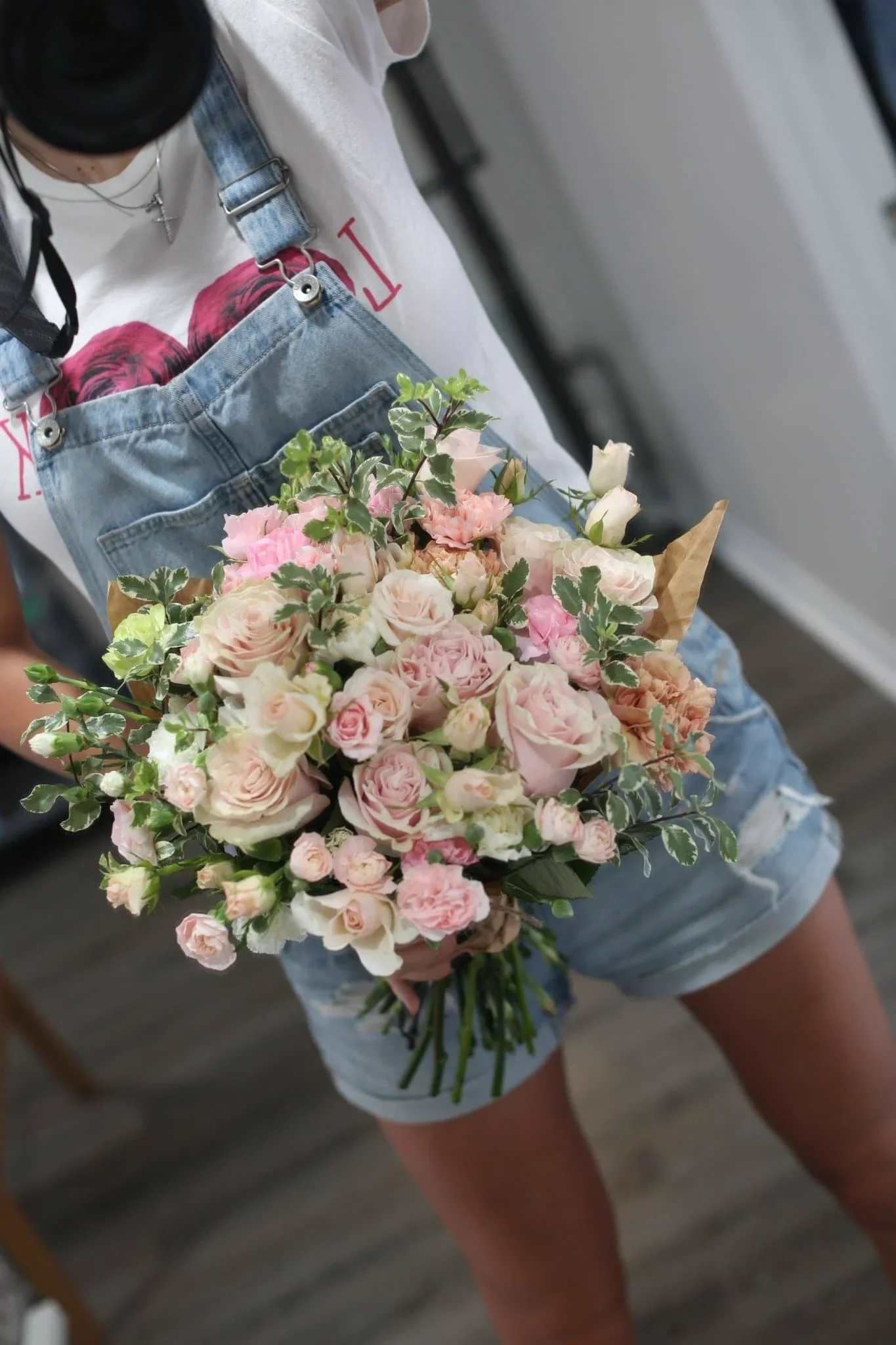 Handheld bouquet of pale pink and white roses with greenery
