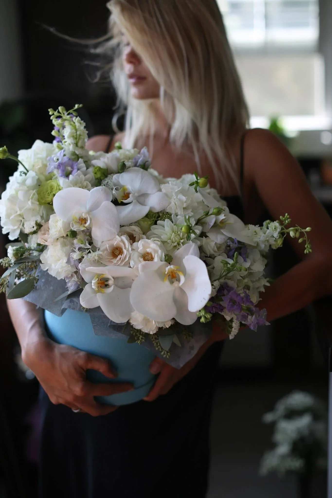 Woman holding a large bouquet of white and lavender flowers