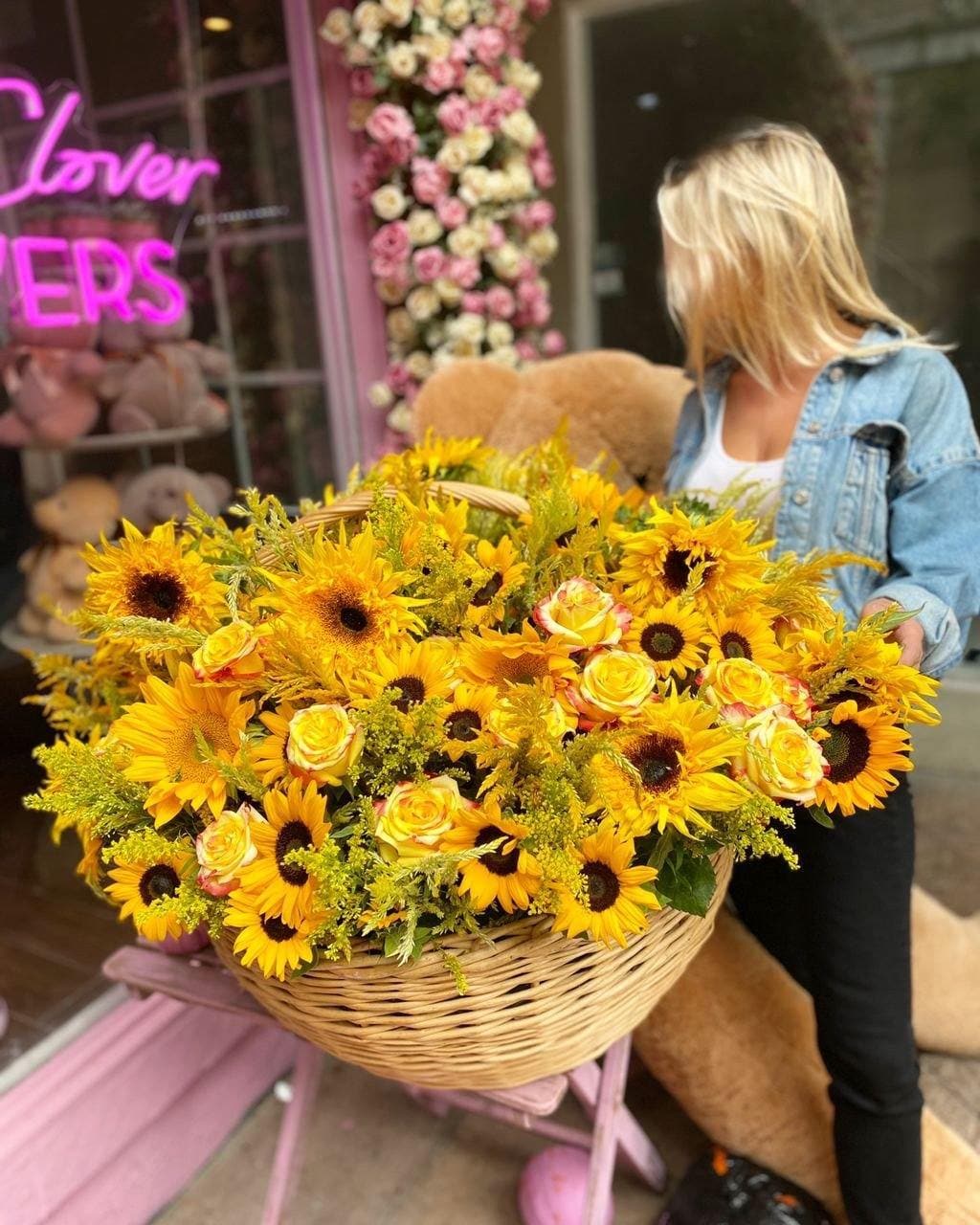 Large basket of sunflowers and yellow roses held by a woman