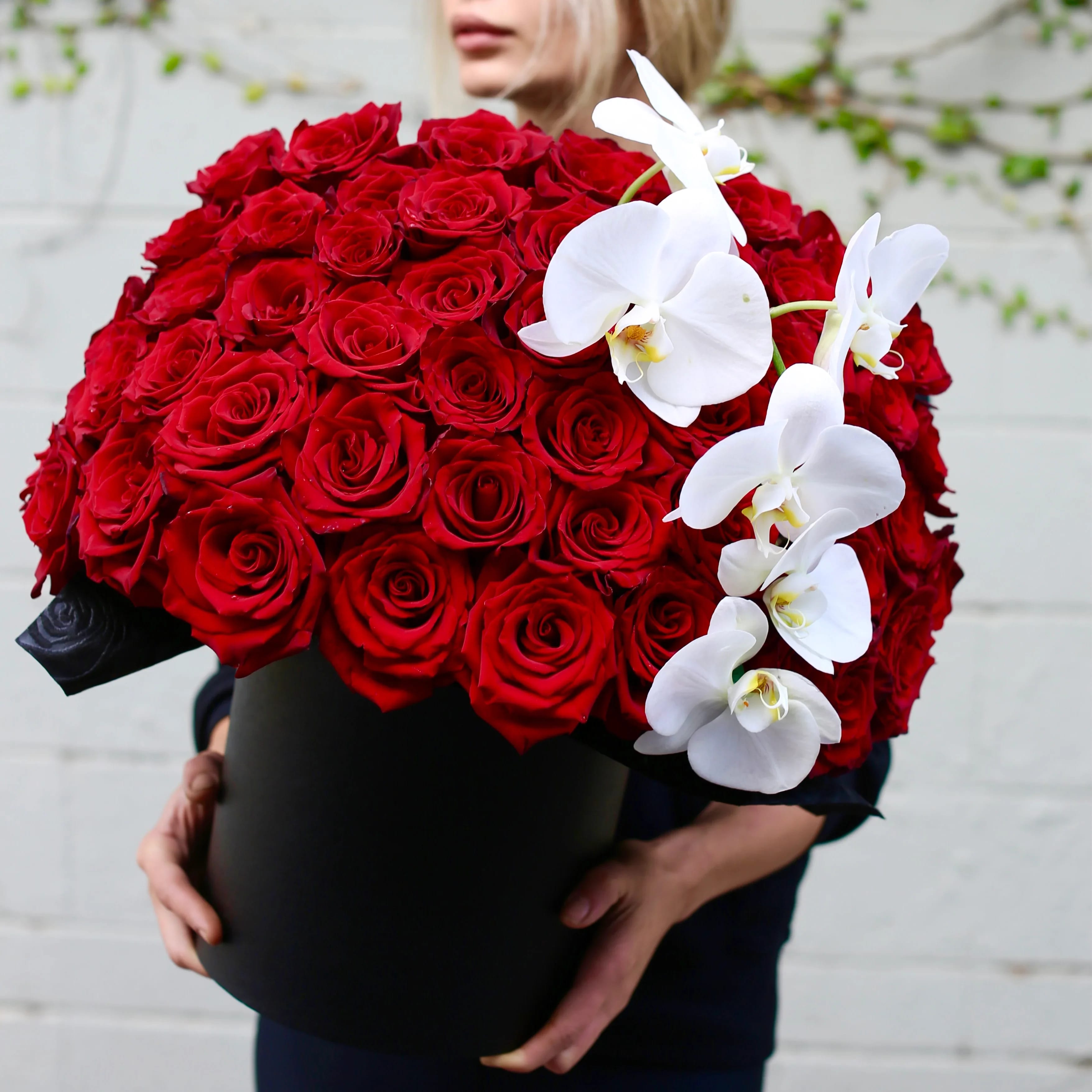 Large bouquet of red roses with white orchids in a black box
