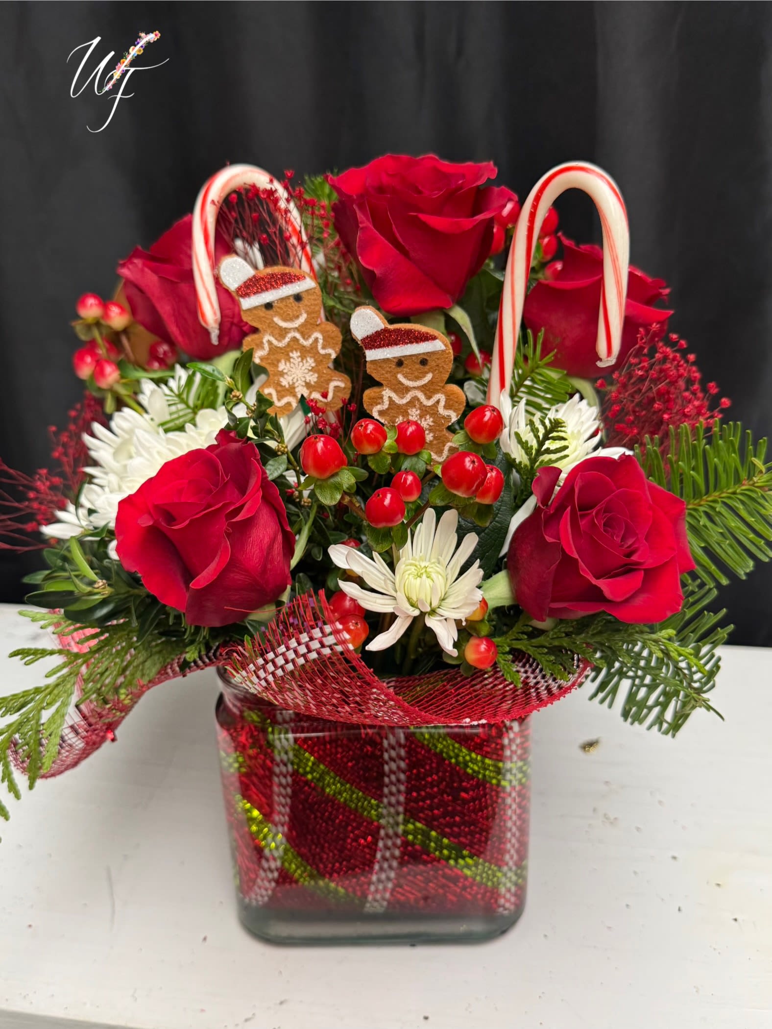 Red roses and white daisies in a glass vase with candy cane decorations
