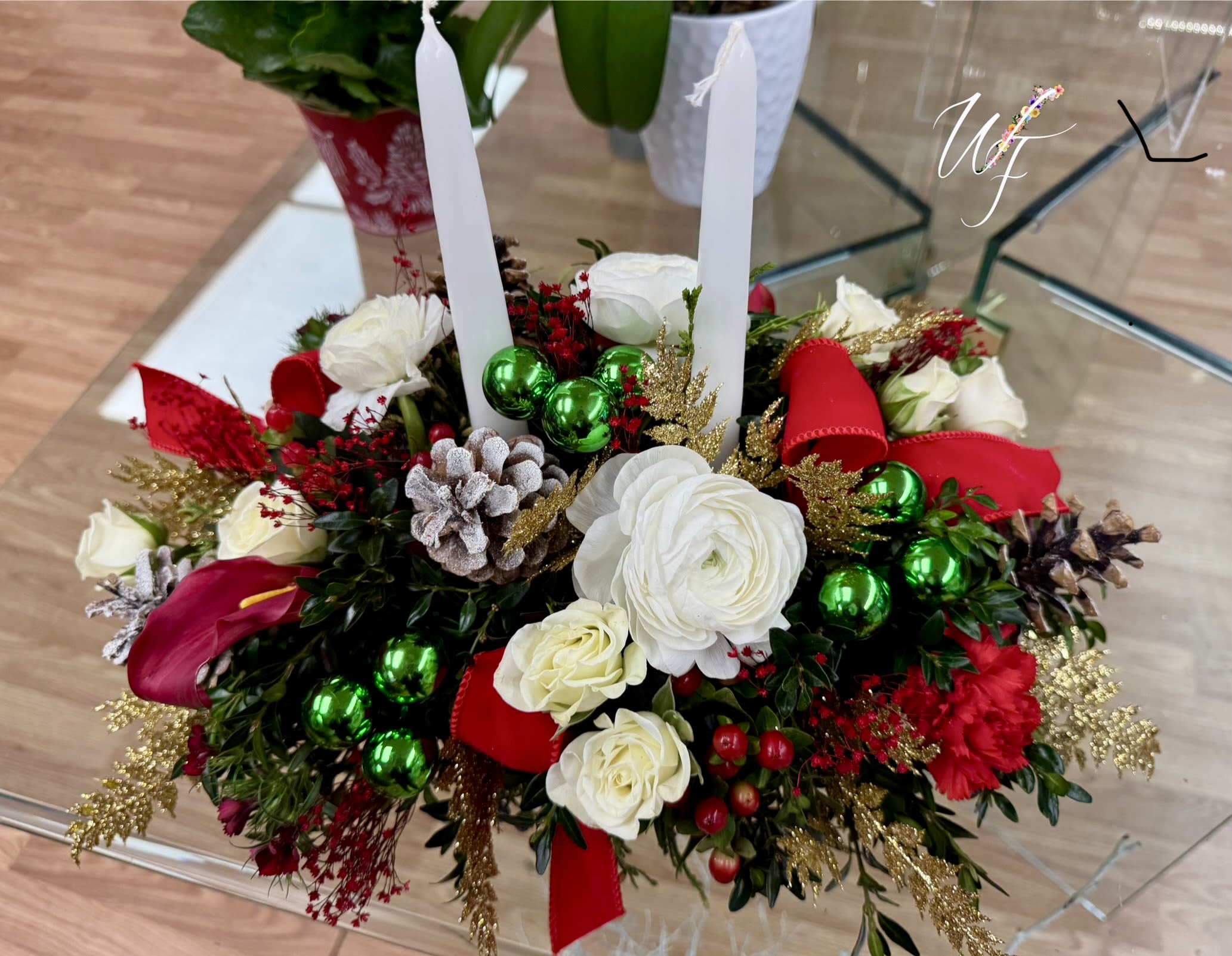 Holiday centerpiece with white flowers, red accents, and two white taper candles