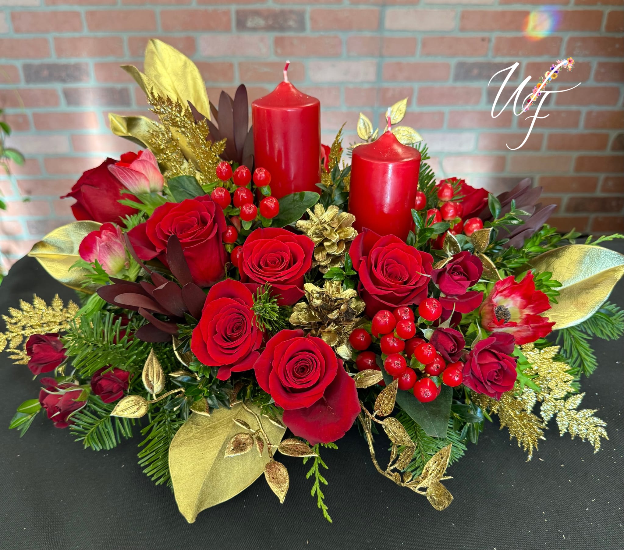 Red roses arranged with two red candles and gold accents
