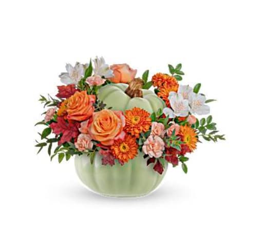 Orange and white flowers arranged in a pale green pumpkin vase