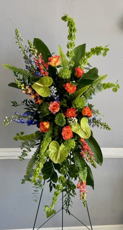 Tall floral spray with orange roses and bright green tropical accents