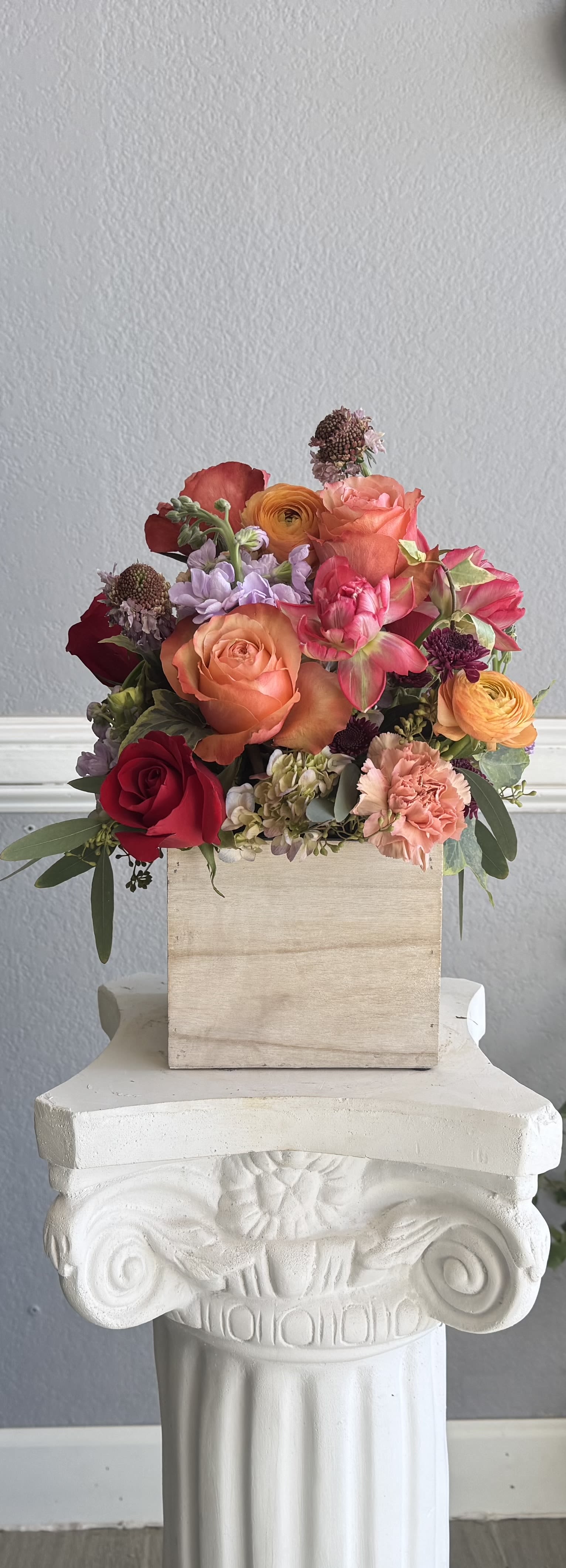 Mixed bouquet of roses, ranunculus, and carnations in a wooden box