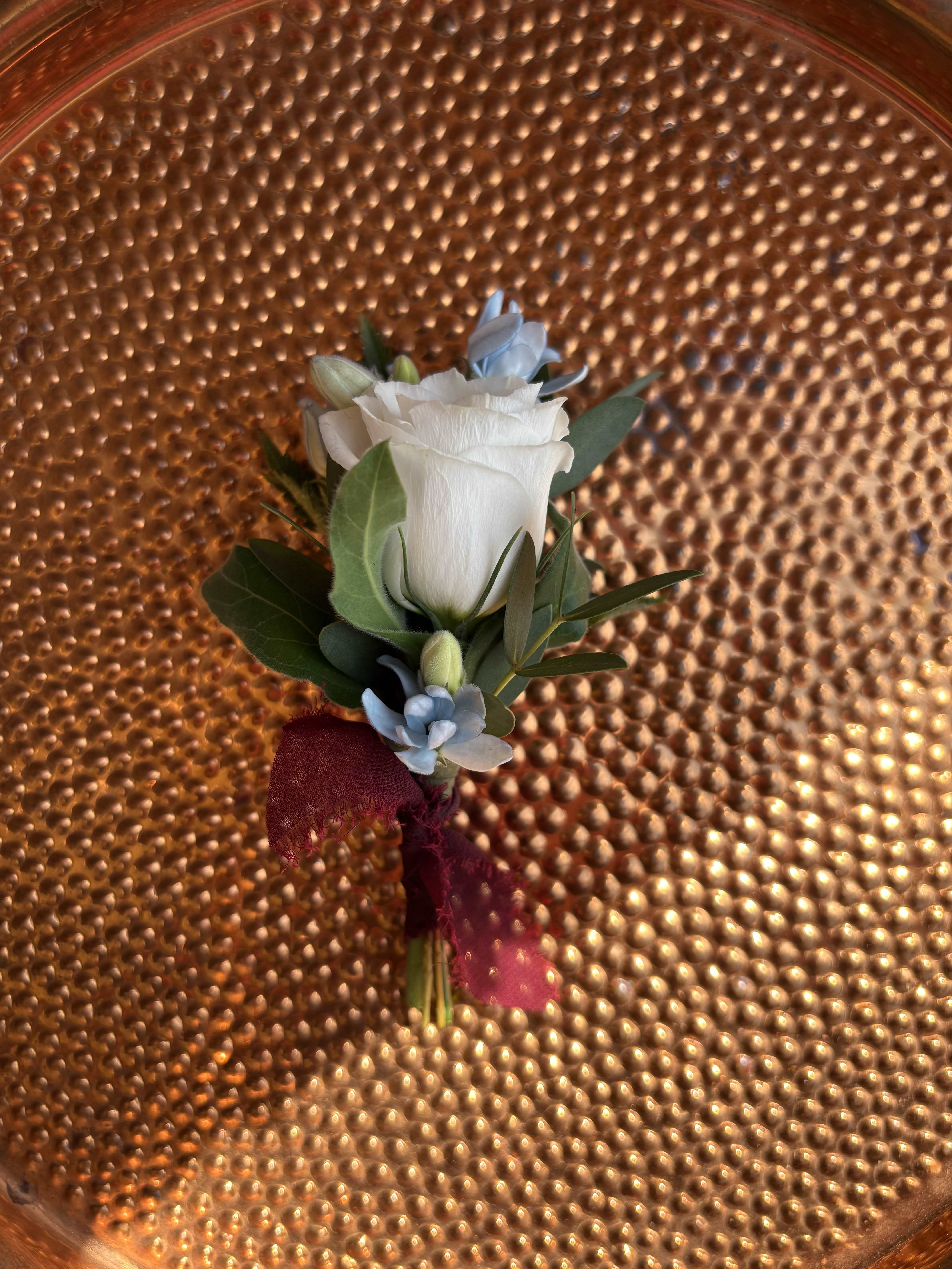 Good Vibes Boutonniere - Keep the good vibes going with this fresh and fun boutonniere — the perfect finishing touch for your homecoming look. Each piece is thoughtfully designed and can be customized to match your style. Choose your ribbon color and flower combo to coordinate with your outfit or date’s corsage. Whether you go classic or bold, this little bloom brings all the charm.