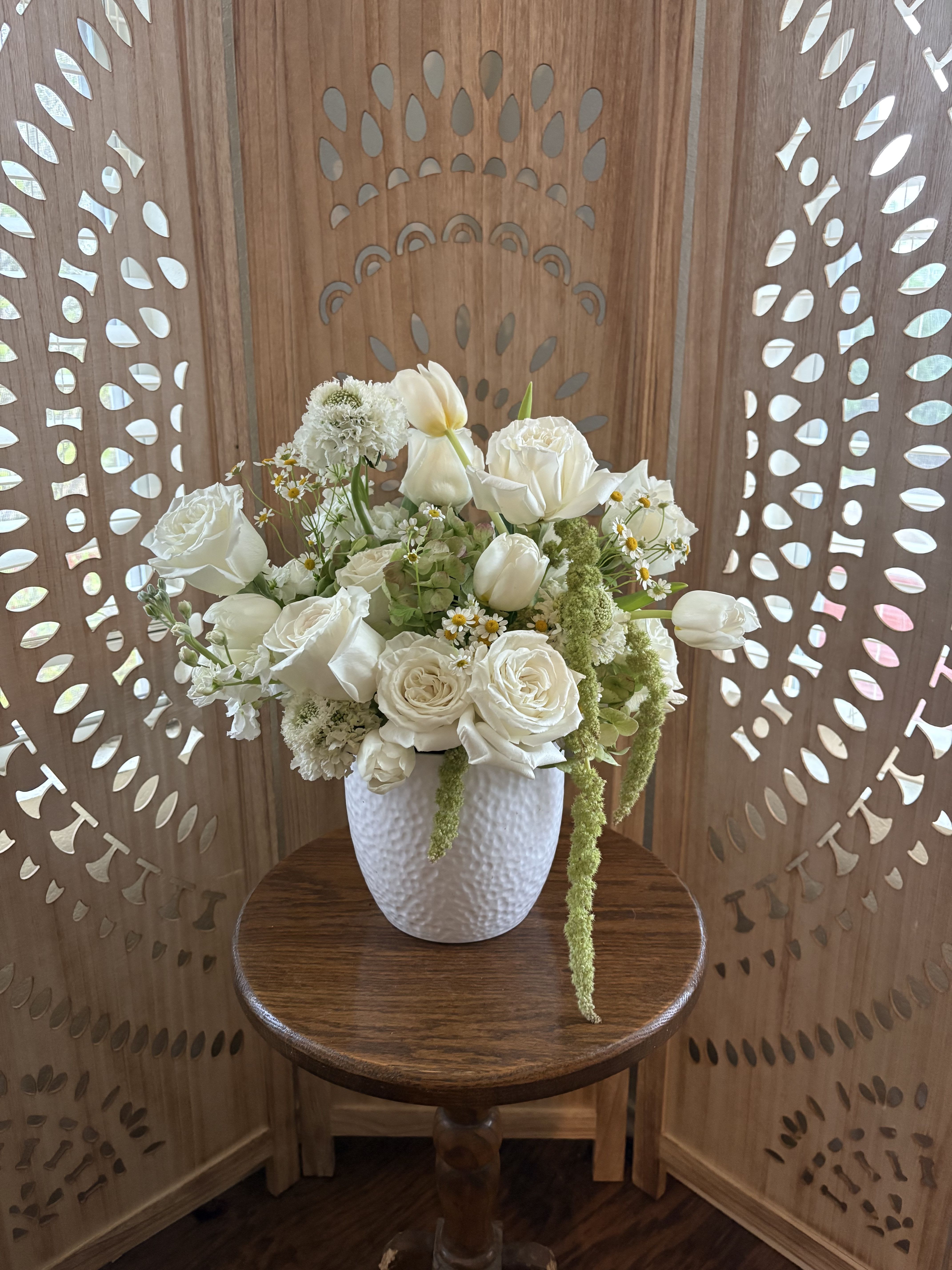 Luna Bloom  - Bring a touch of ethereal elegance to any space with Luna Bloom. This all-white arrangement features velvety white roses, delicate white tulips, and charming chamomile, arranged in a crisp white ceramic pot. Soft, airy, and effortlessly graceful, it evokes the calm of moonlight and the quiet magic of a serene garden. Perfect for adding a serene, uplifting touch to your home or gifting a moment of peaceful beauty.