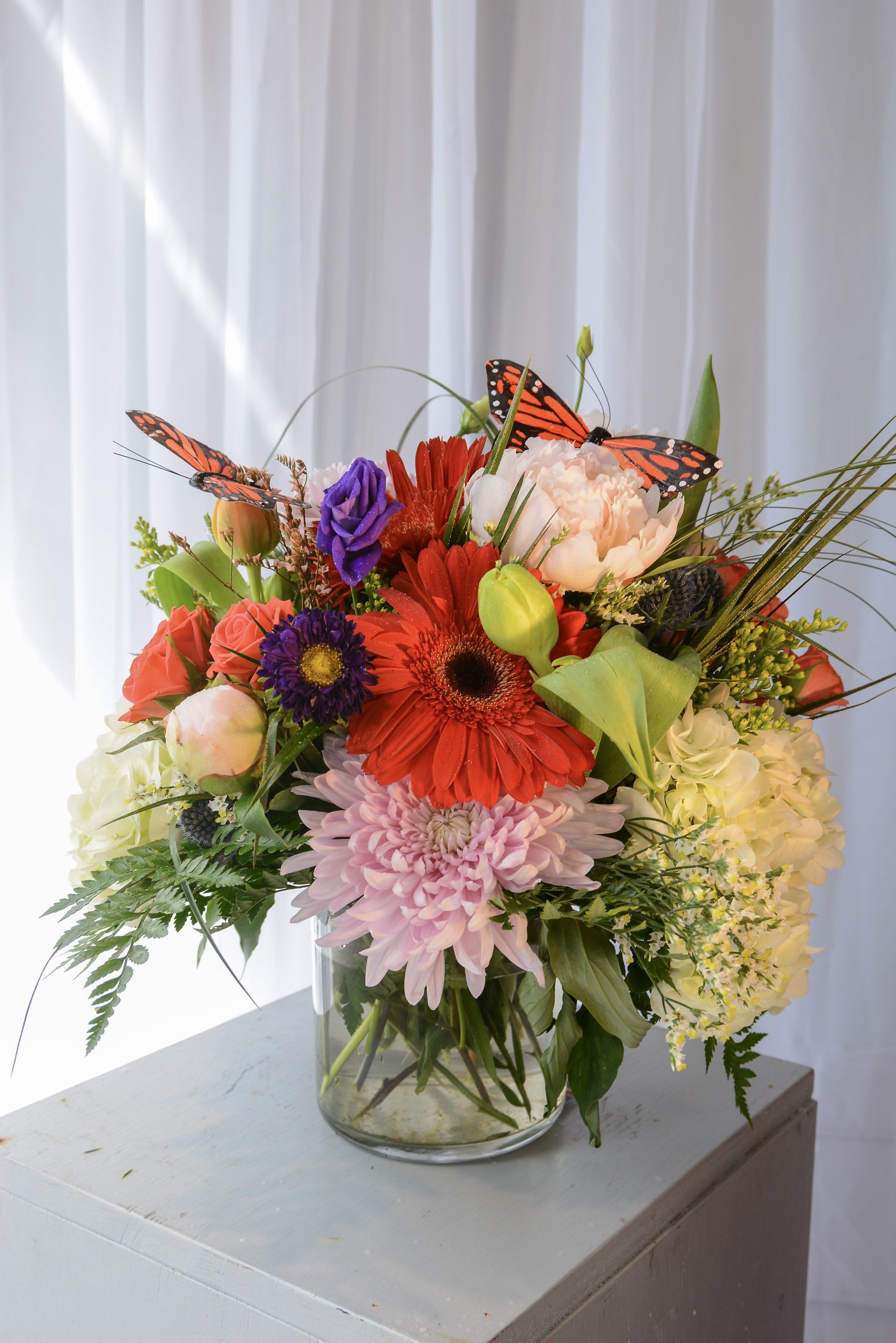 Mixed bouquet in a glass vase with bright flowers and butterfly accents