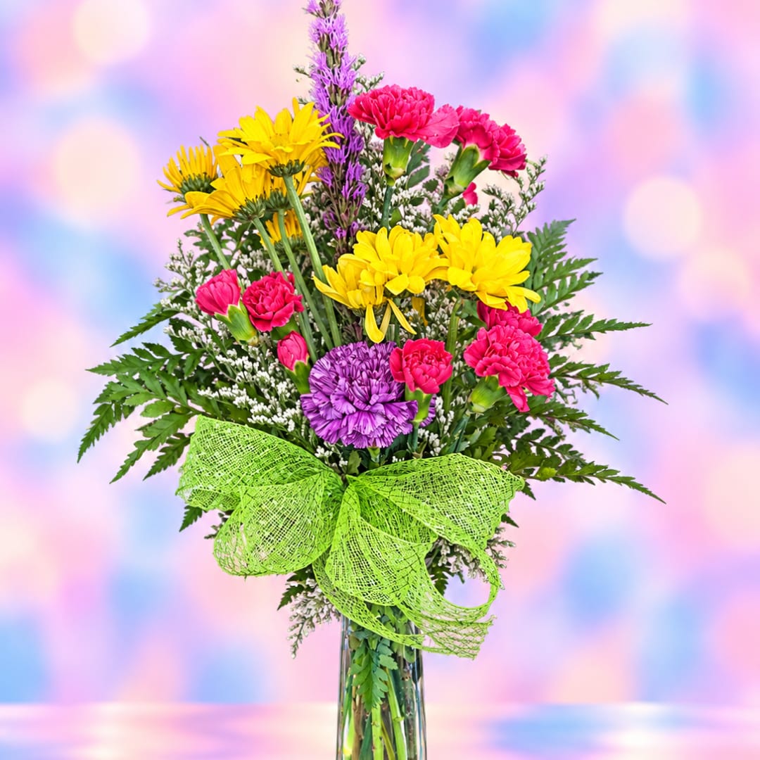 Bouquet of yellow, pink, and purple flowers in a glass vase with a green bow