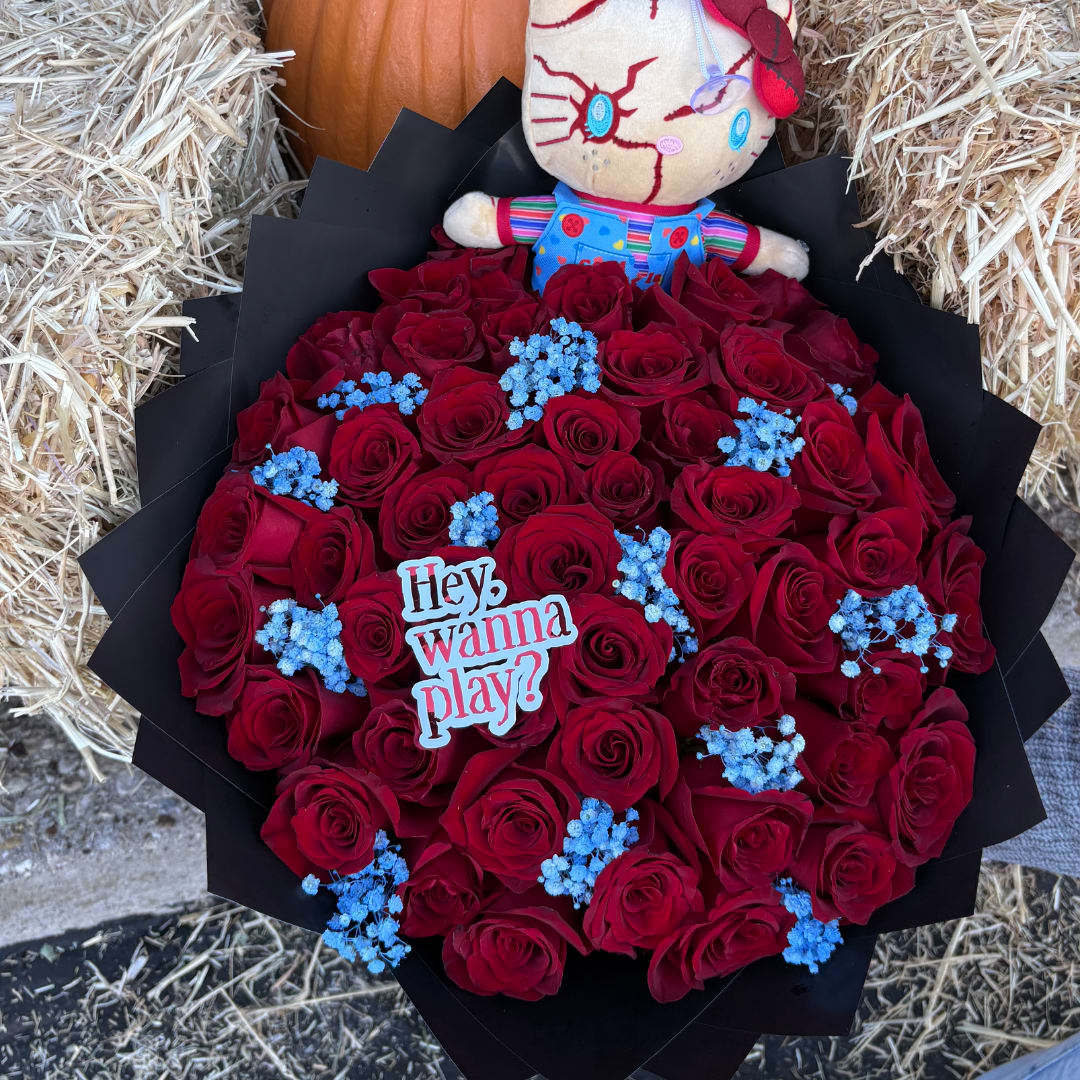 Bouquet of red roses with blue filler flowers and a plush doll topper