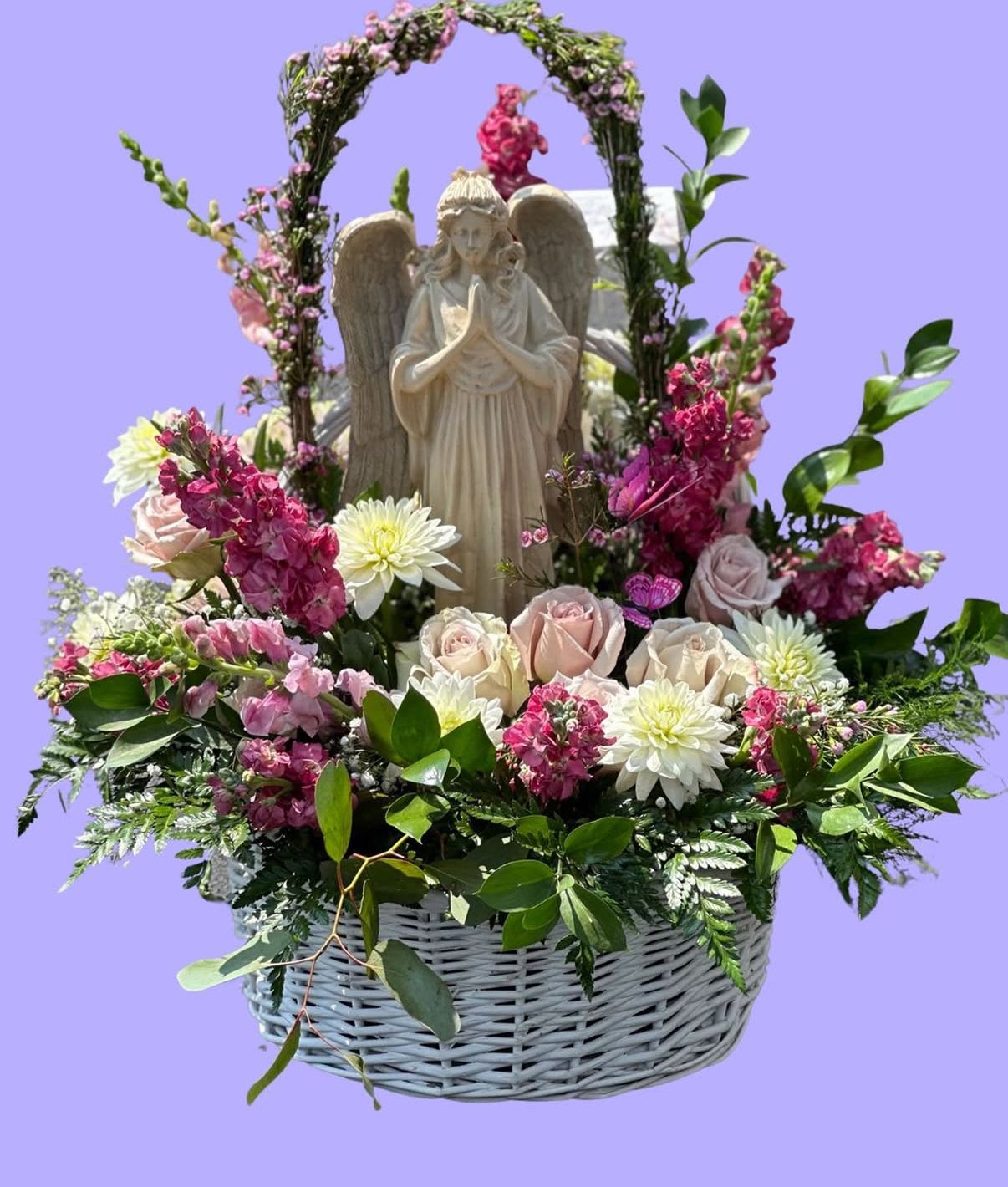 Basket arrangement with an angel statue, pink and white flowers, and greenery