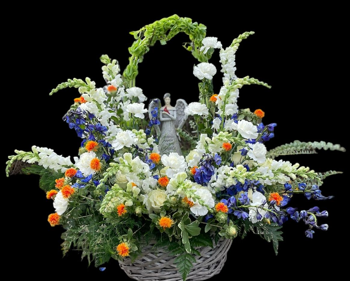 Heavens Serenity - "Discover the tranquil beauty of our 'Heaven's Serenity Angel Basket'. This exquisite floral arrangement is a heartfelt tribute, featuring a graceful angel statue nestled amidst a cloud of pristine white Delphiniums and Stocks, complemented by calming blue Delphiniums and vibrant orange Safflower accents. Presented in a charming wicker basket, this piece offers a sense of peace, comfort, and enduring remembrance, making it a truly meaningful gesture for a loved one or a serene addition to any space."