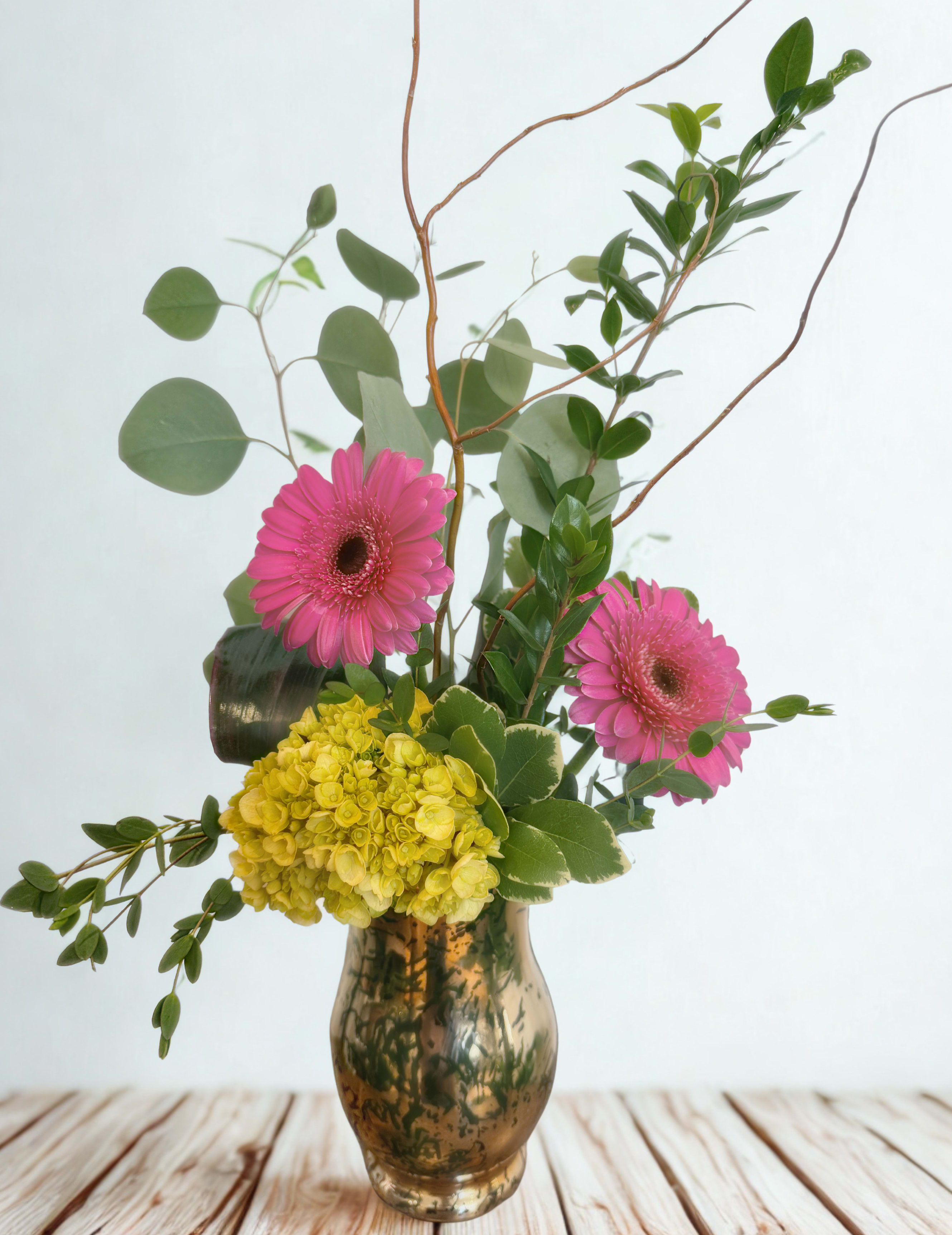 Pink gerbera daisies and yellow hydrangea in a glass vase