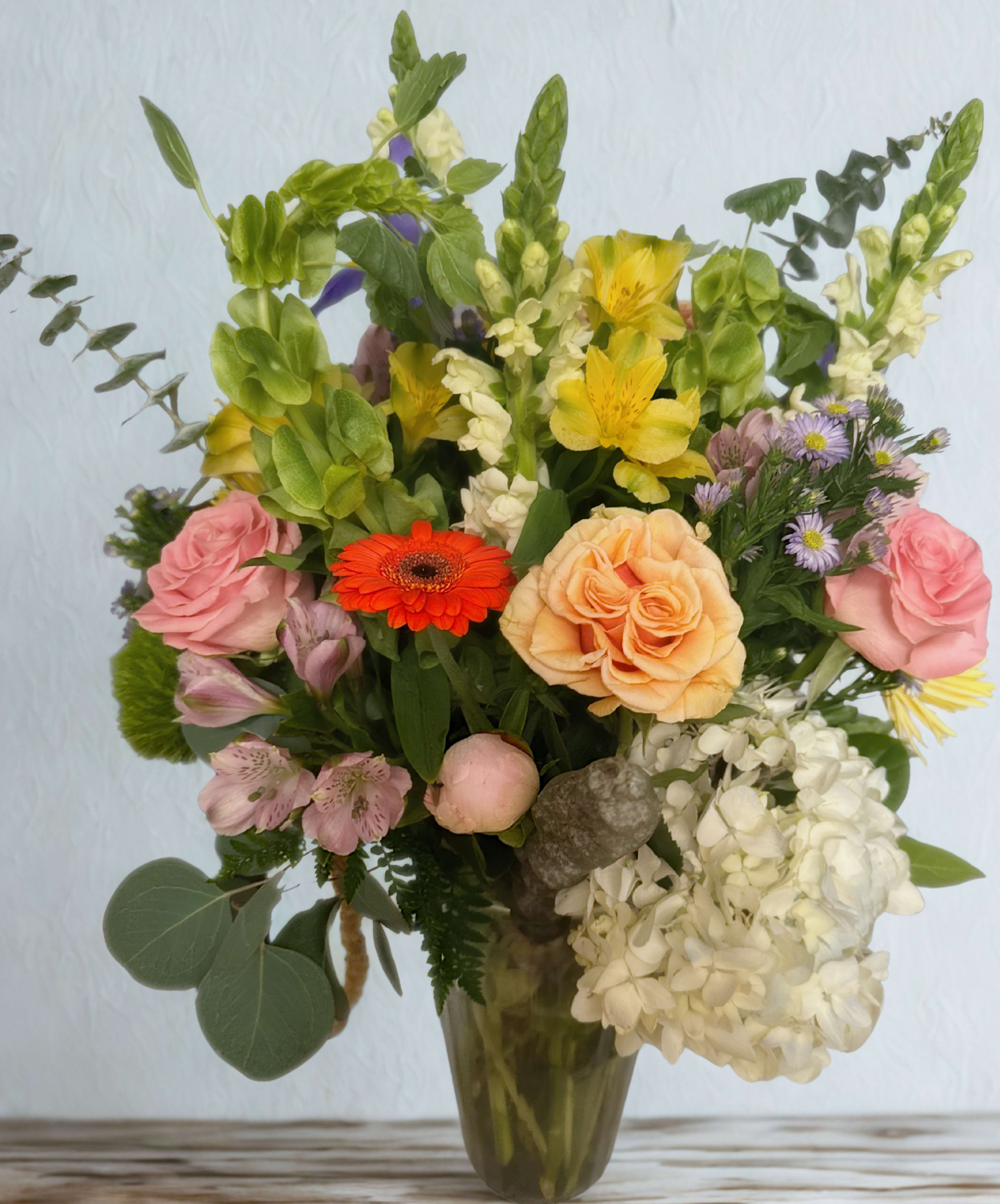 Mixed bouquet in a glass vase with roses, lilies, and hydrangeas
