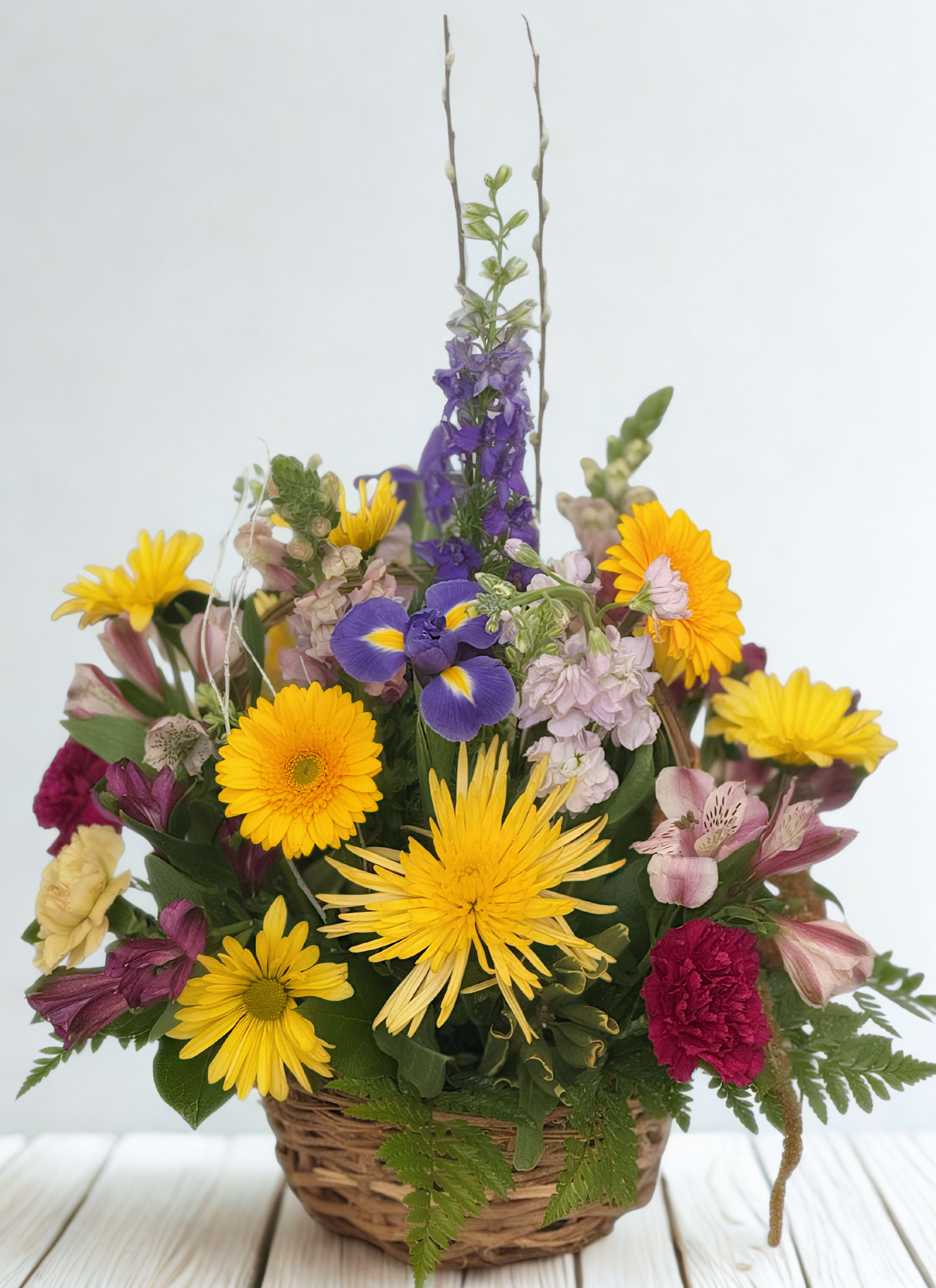 Mixed flower basket with yellow daisies, purple iris, and pink blooms