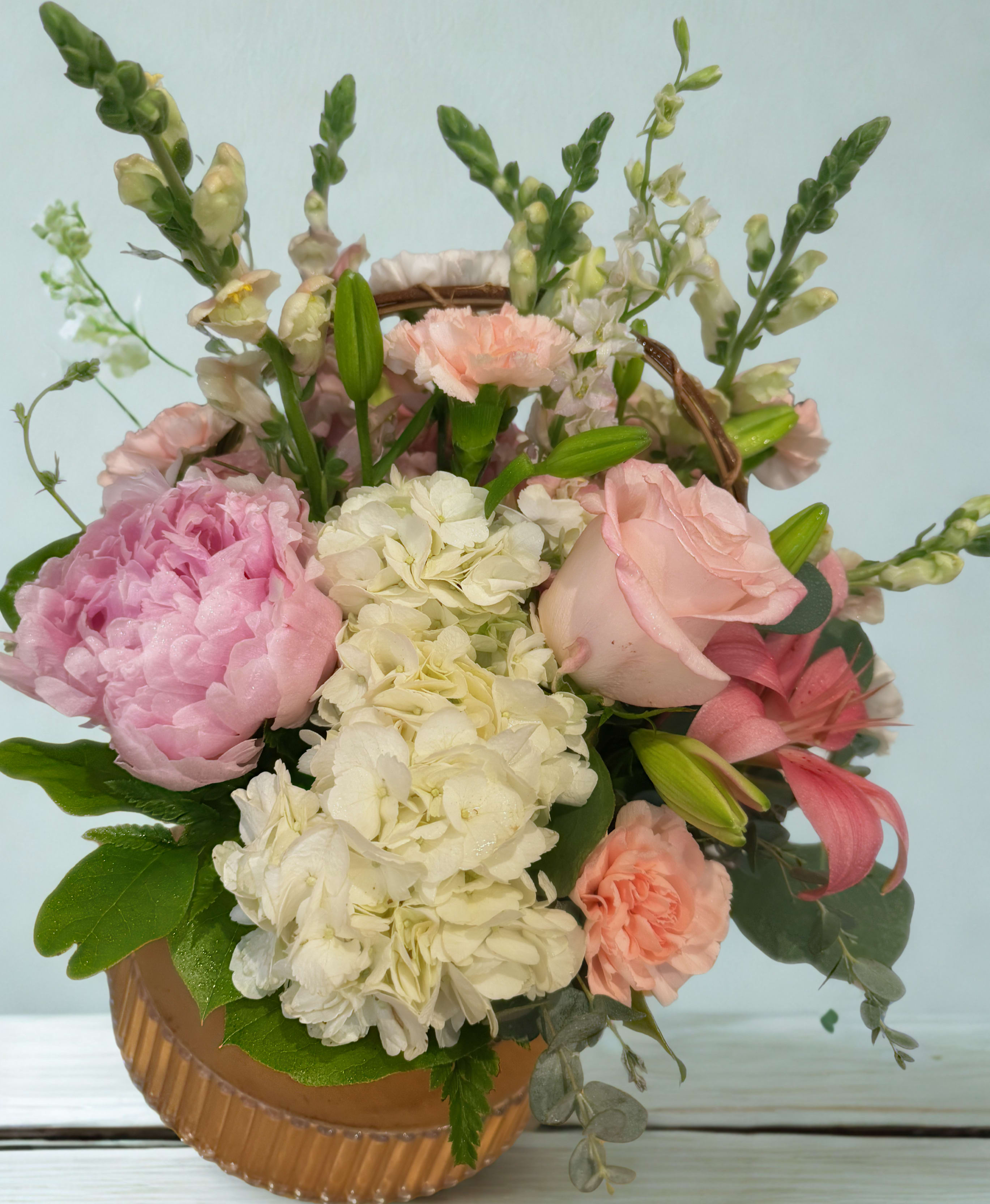 Pink and white floral arrangement in a round basket container