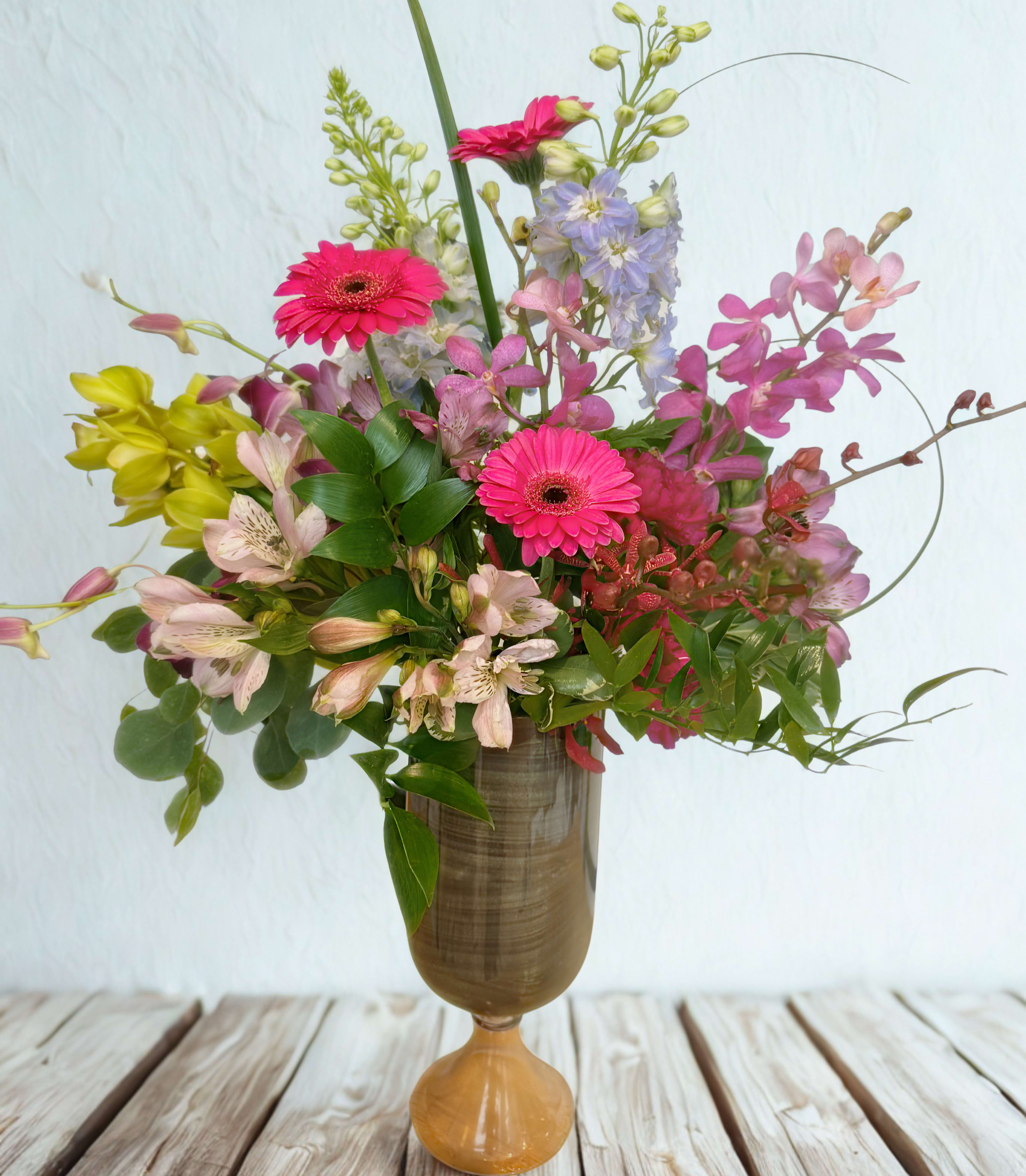 Mixed bouquet of pink gerberas and pastel flowers in a tall vase