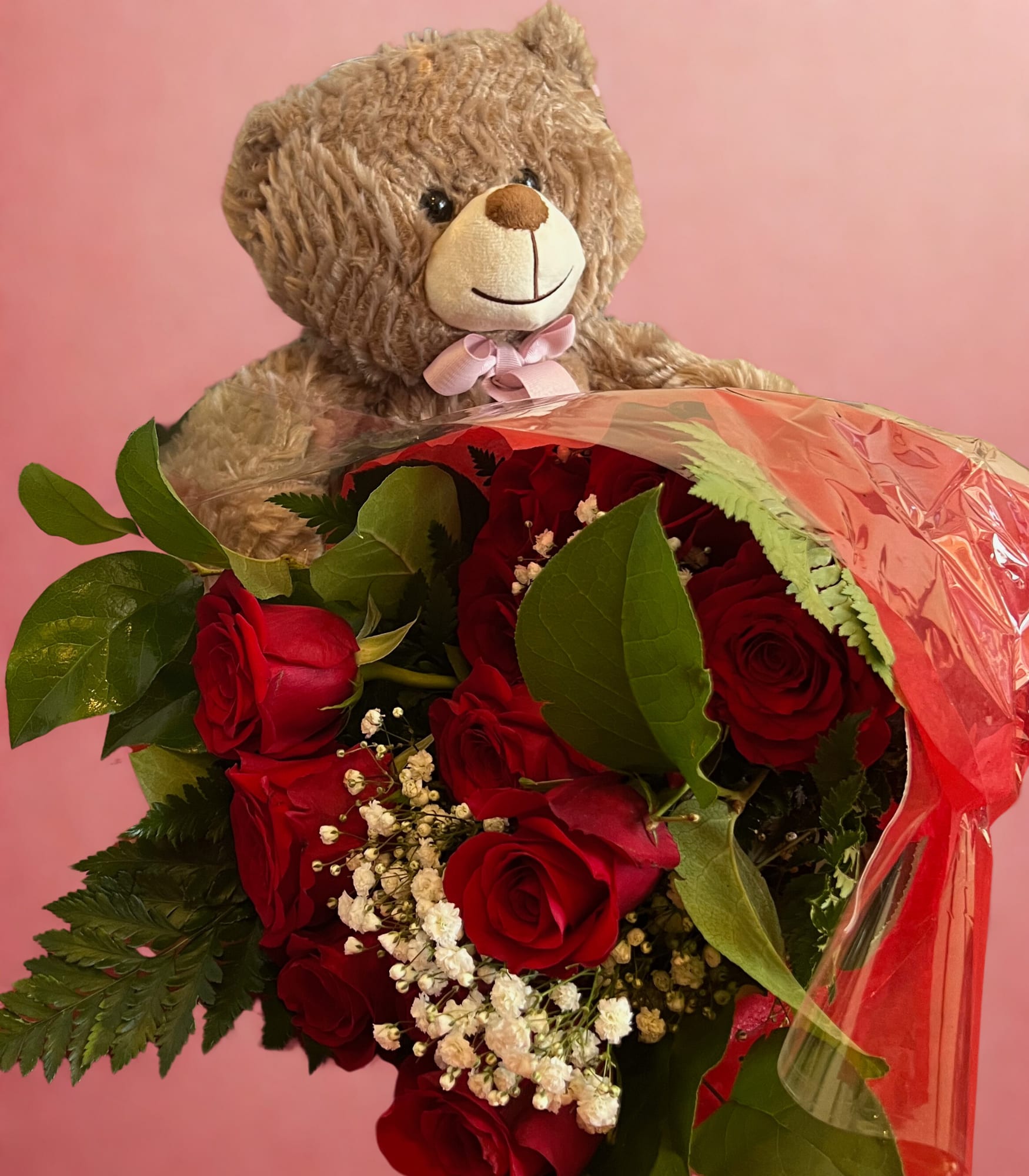 Teddy bear holding a bouquet of red roses