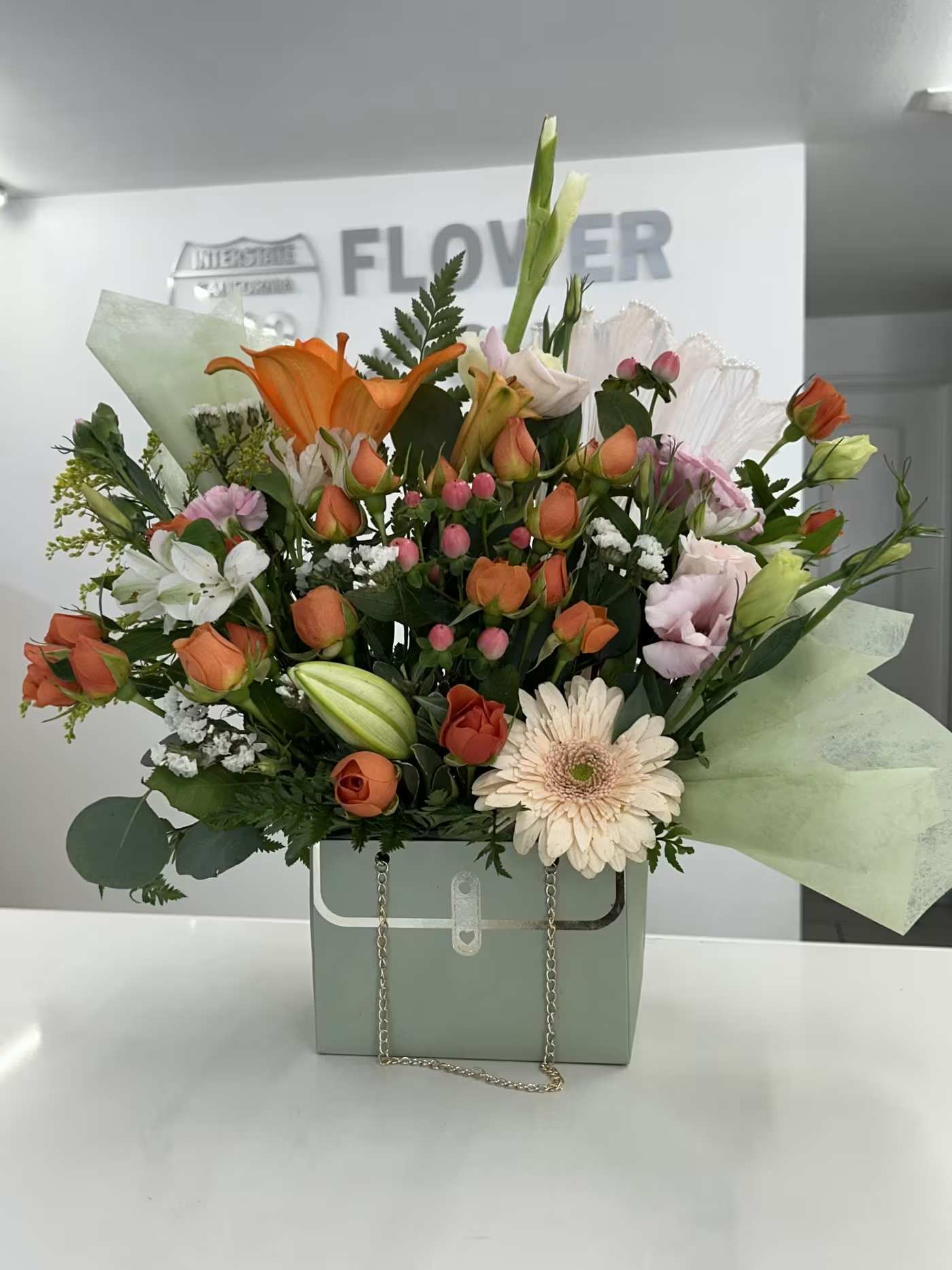 Blushing Garden Purse - Soft, warm, and effortlessly charming, Blushing Garden features a delicate blend of peach and blush roses, vibrant gerbera daisies, and seasonal blooms nestled in fresh greenery. Designed in a pastel handbag-style box, this arrangement captures the feeling of a sunlit garden in full bloom — perfect for birthdays, thank-you gifts, celebrations, or simply brightening someone’s day.