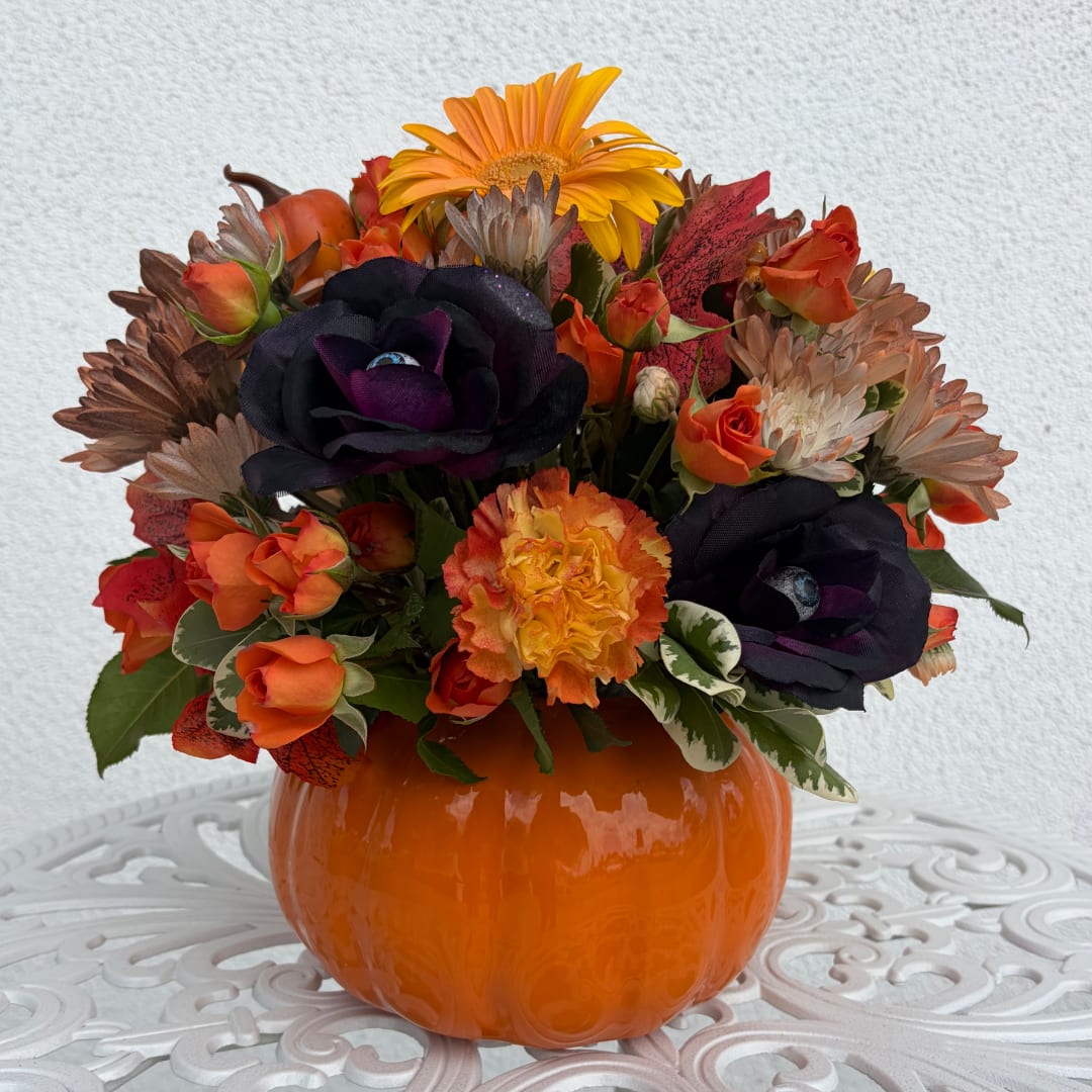 Orange and black floral arrangement in a pumpkin-shaped vase