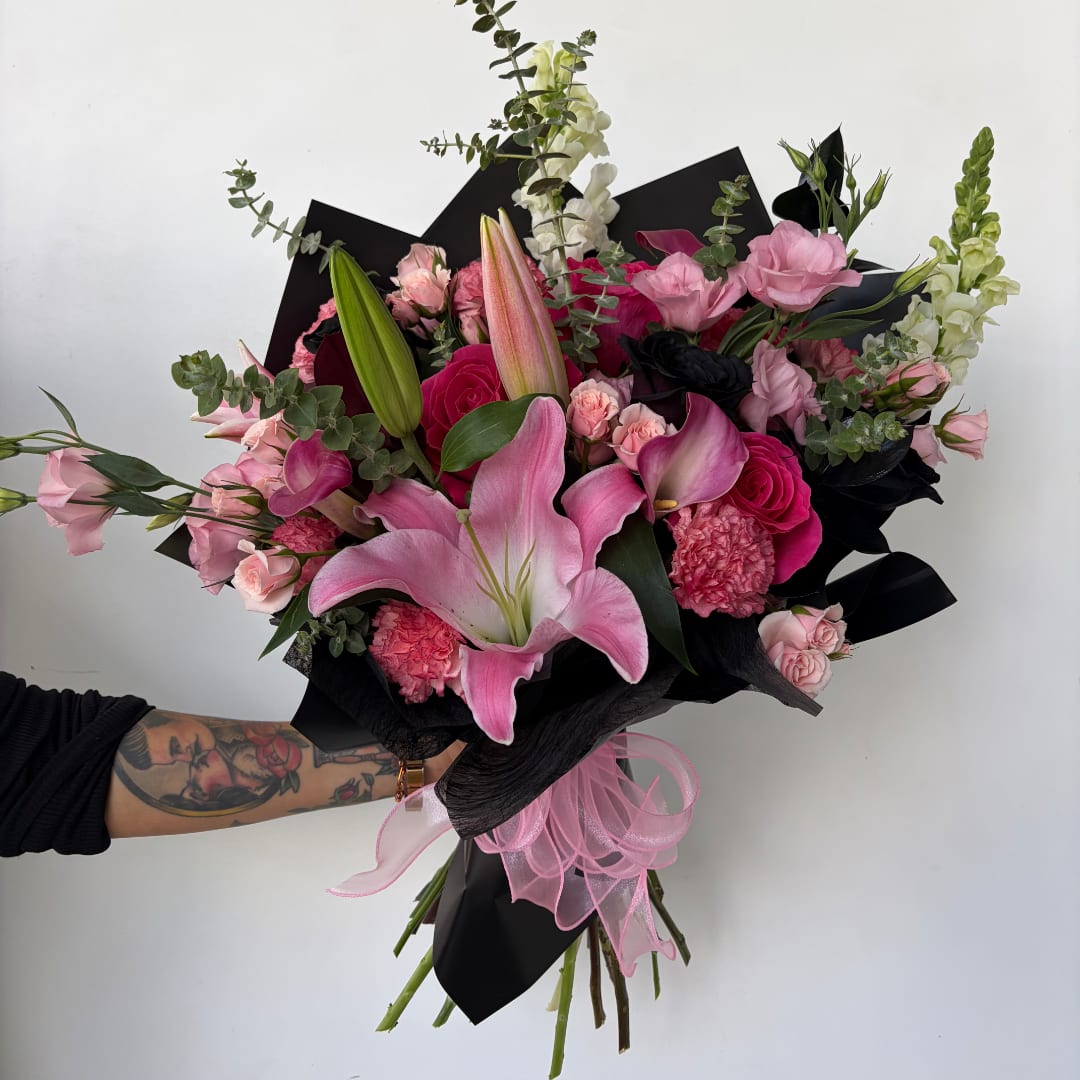 Pink lily and rose bouquet wrapped in black paper with a pink ribbon