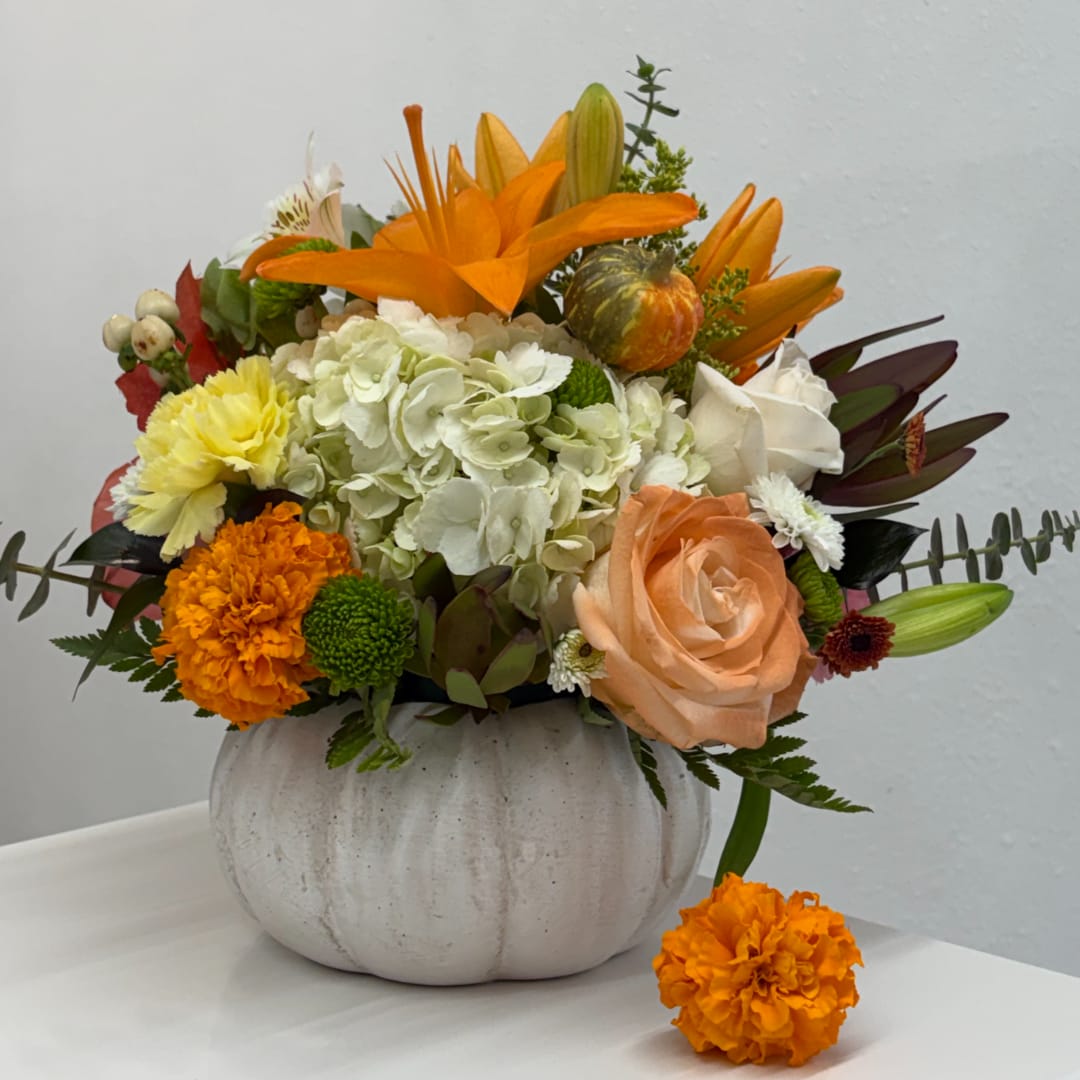 Flores para Recordar - A beautiful expression of remembrance, designed with soft seasonal tones and vibrant pops of color. Presented in a charming white pumpkin vase, this arrangement is a lovely way to honor loved ones and celebrate the memories that live on. (If you'd like to change any colors please leave note in instructions. If some flowers and/or the vase are not available there will be minor substitutions.)