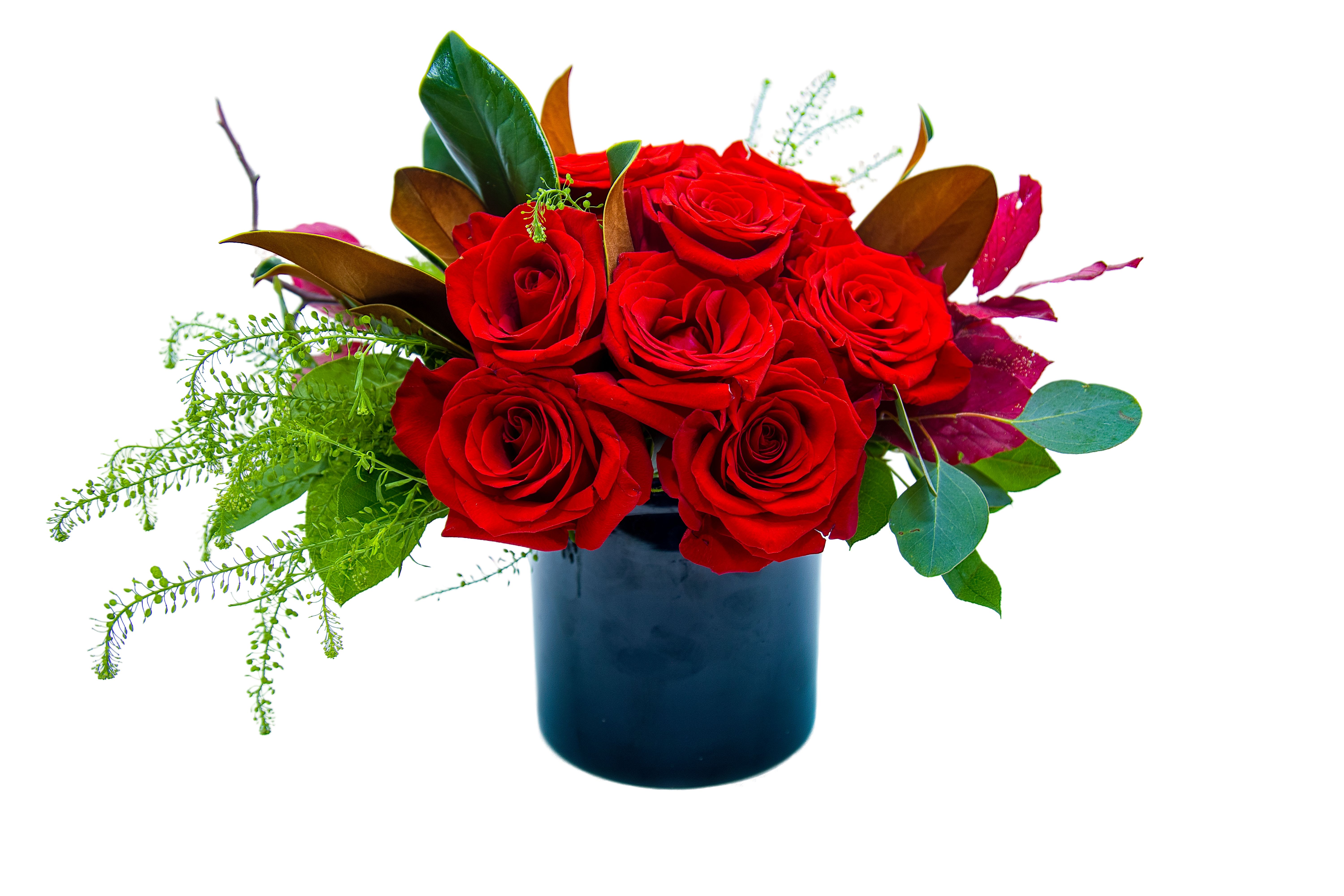 Red roses arranged in a dark blue vase with mixed greenery