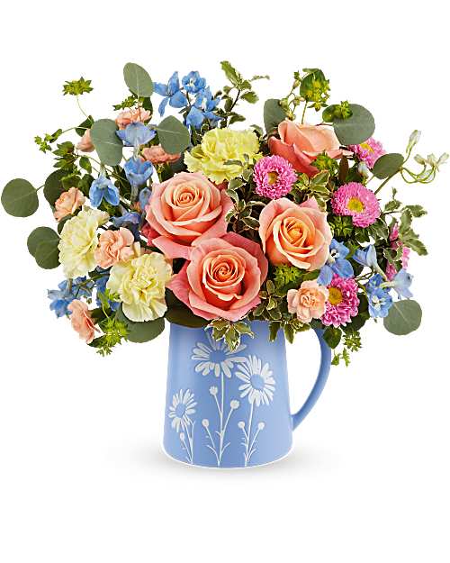 Mixed bouquet of roses, daisies, and blue flowers in a blue pitcher