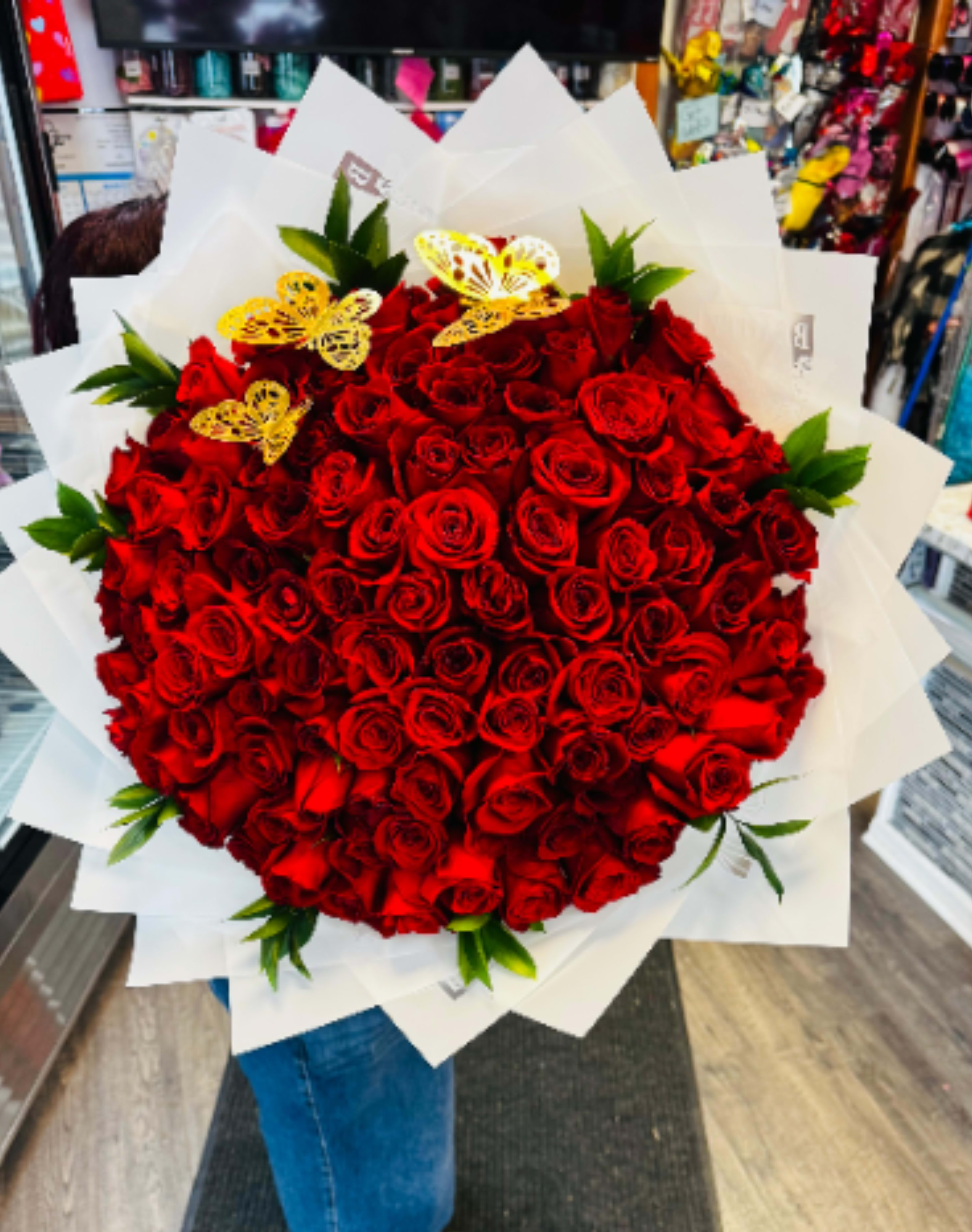 Large bouquet of red roses wrapped in white paper with yellow butterfly accents