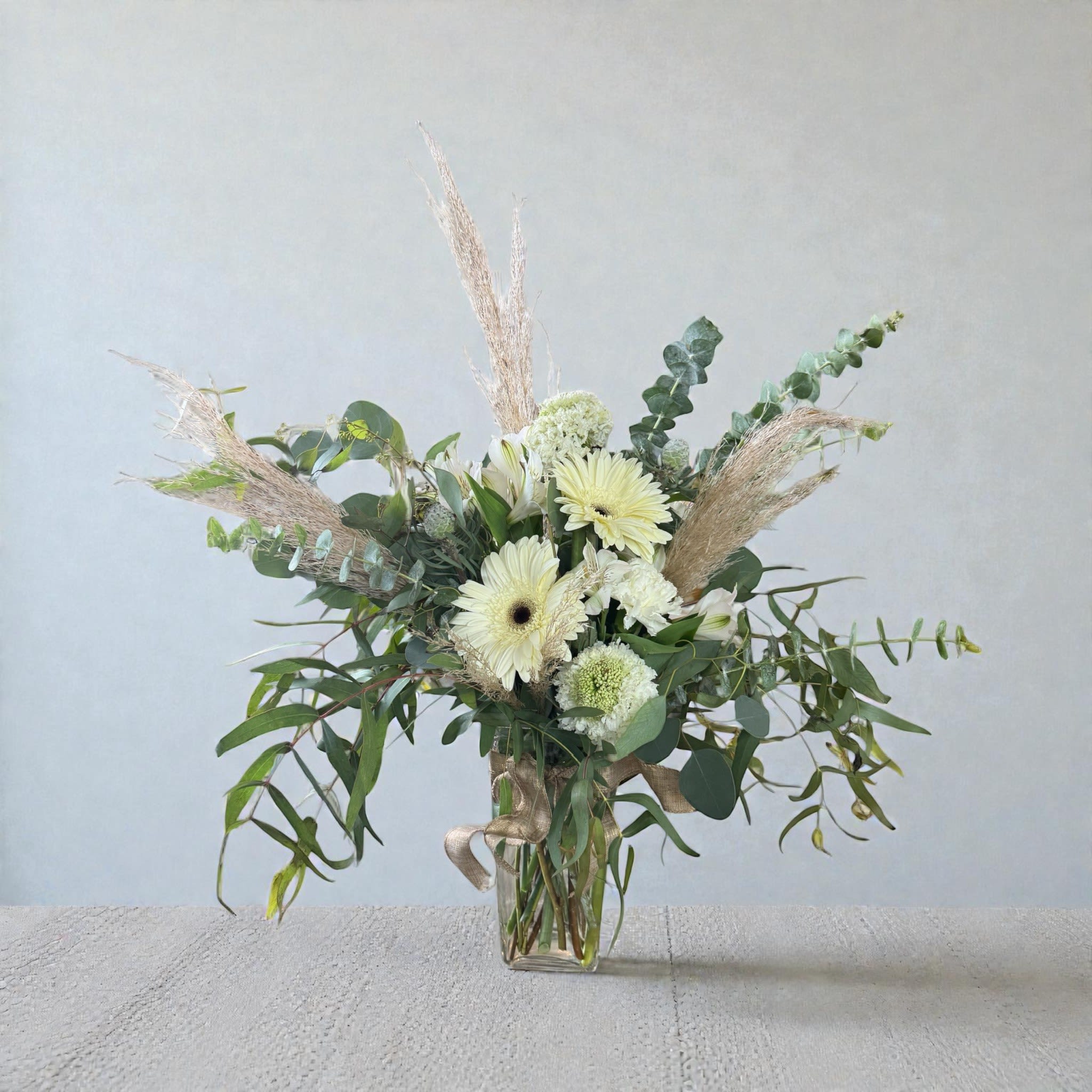 White gerbera daisies and greenery in a clear glass vase