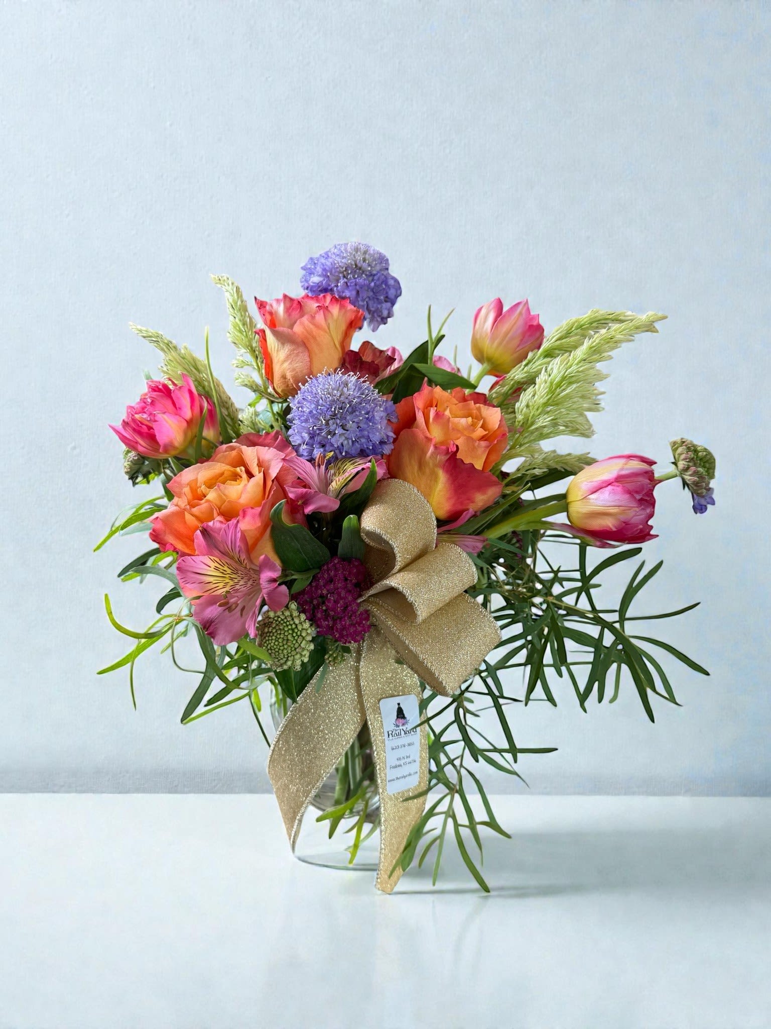 Bouquet of pink and orange roses with purple blooms in a glass vase