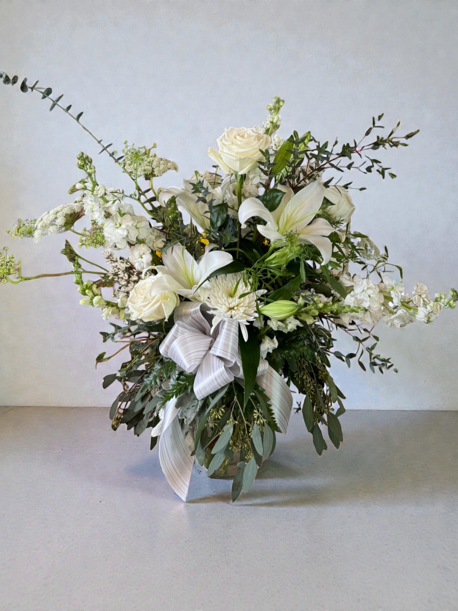 White floral arrangement with roses and lilies in a vase