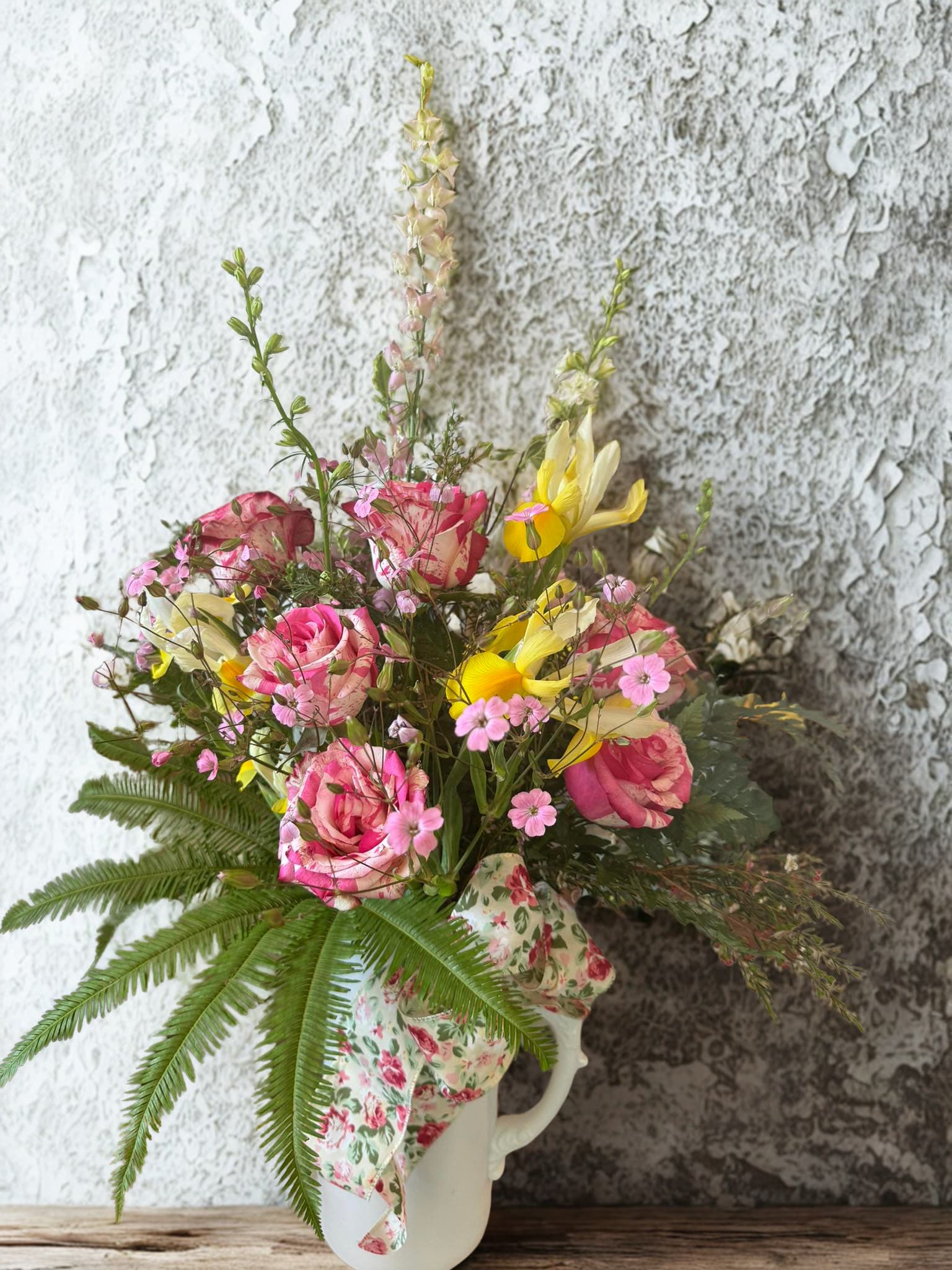 Pink and yellow mixed bouquet in a white pitcher vase